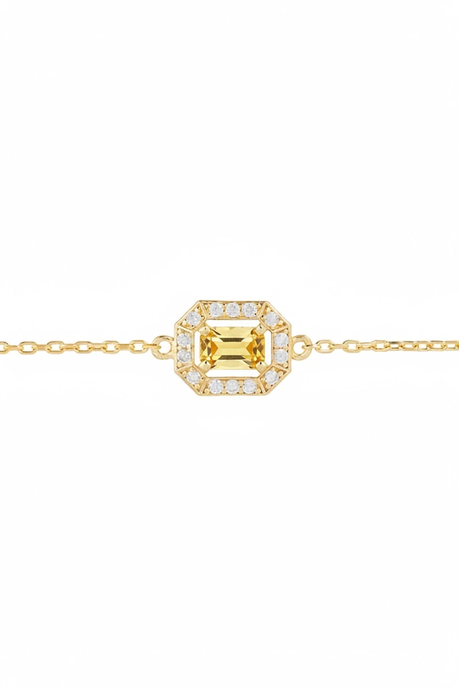 Gold bracelet with a green gemstone in the centre surrounded by diamonds