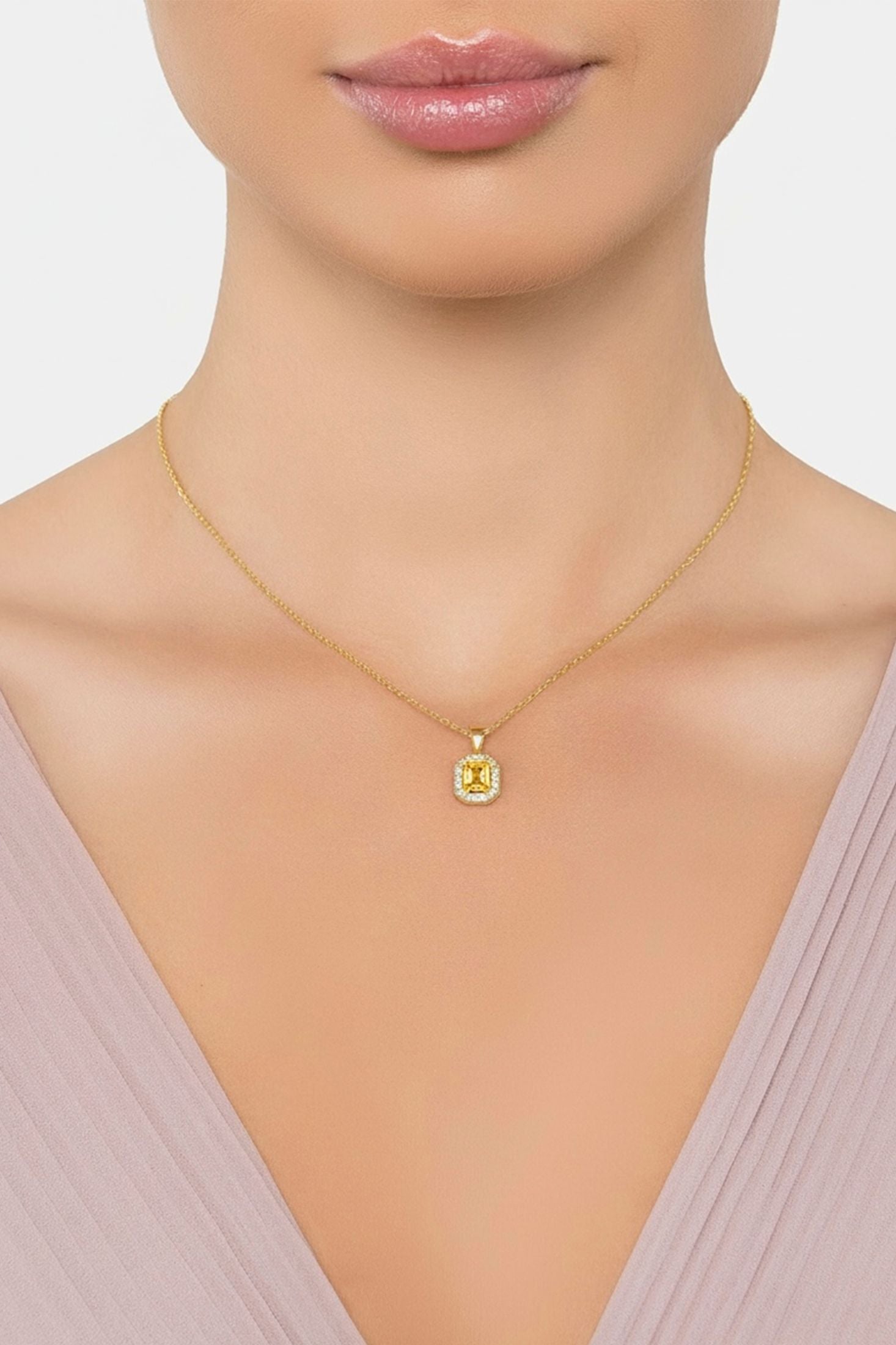 Gold necklace with a green gemstone pendant on a neutral background