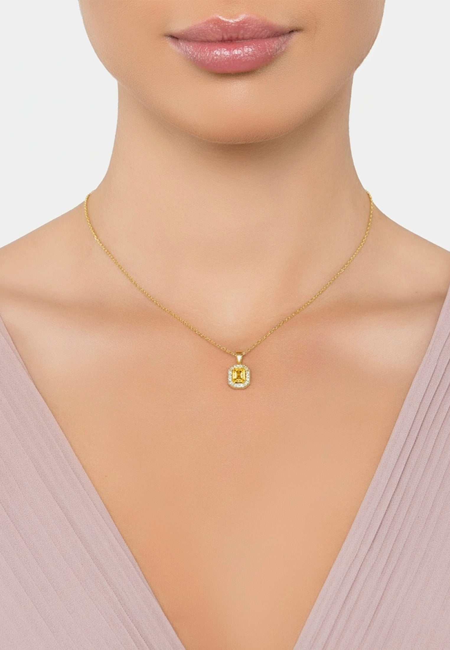 Gold necklace with a green gemstone pendant on a neutral background