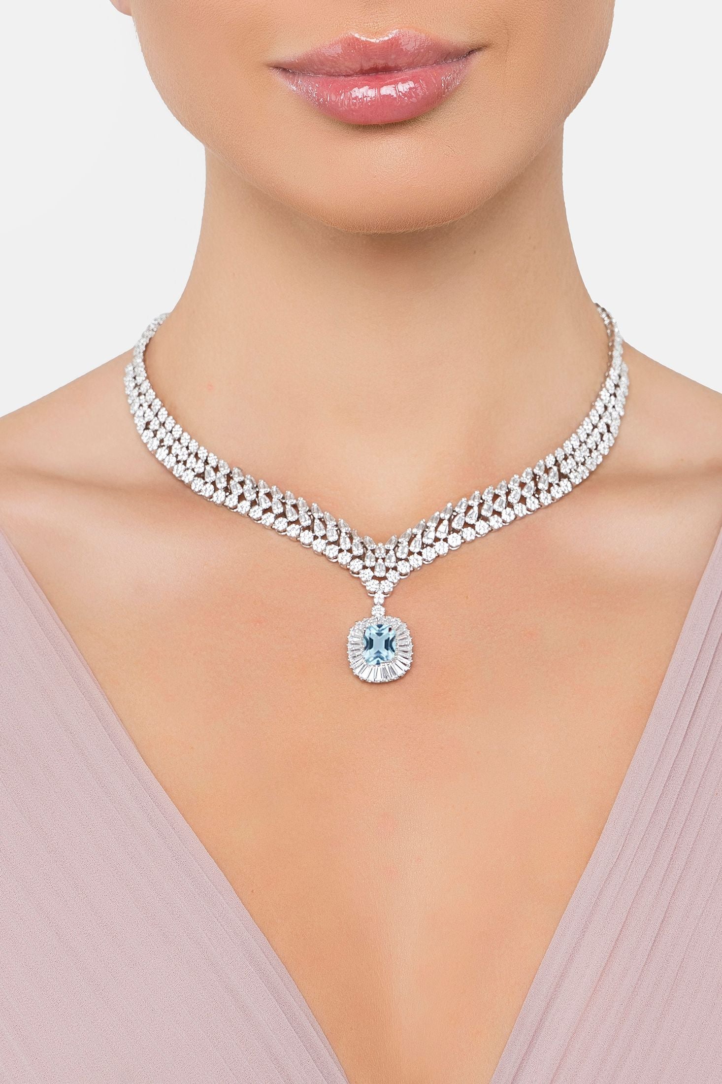 Silver necklace with a central blue gemstone on a model against a neutral background