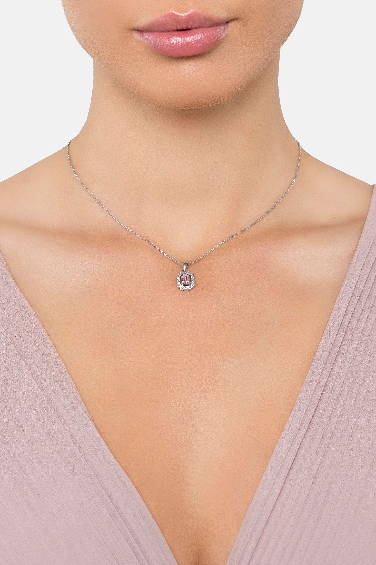 Necklace with a pink pendant worn by a person against a neutral background