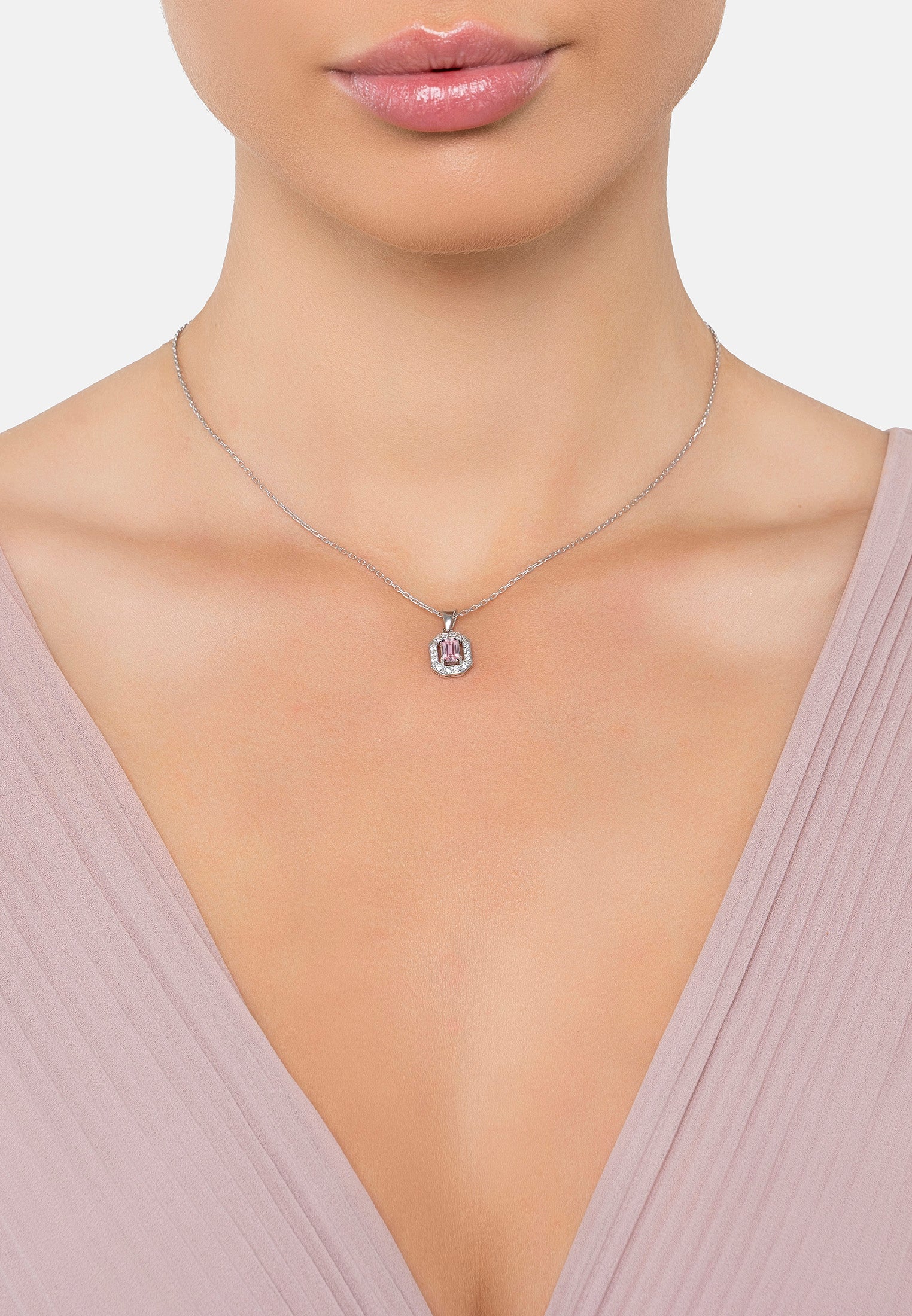 Necklace with a pink pendant worn by a person against a neutral background