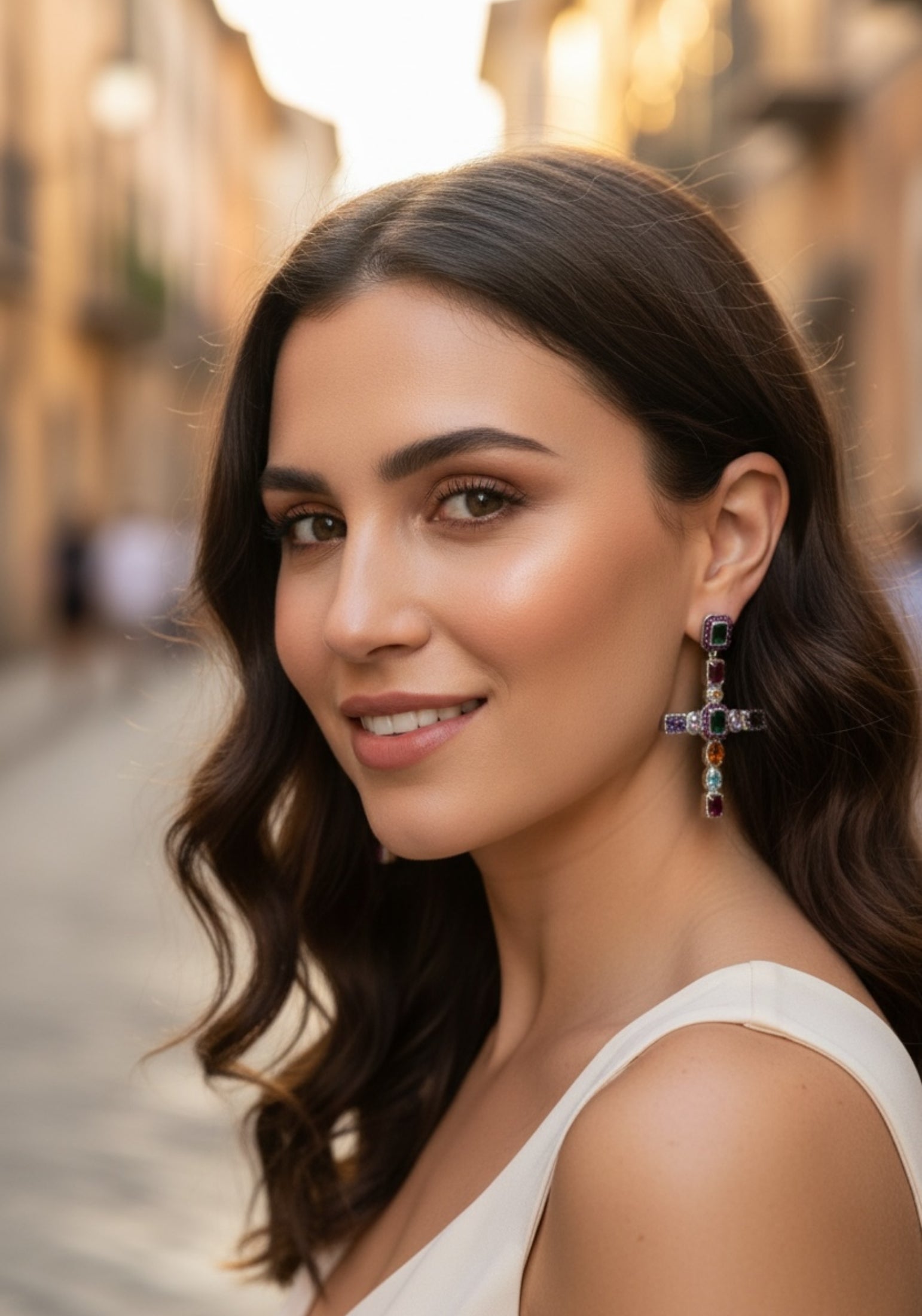 Woman with styled hair and large cross earrings with multicoloured gemstones in an urban setting