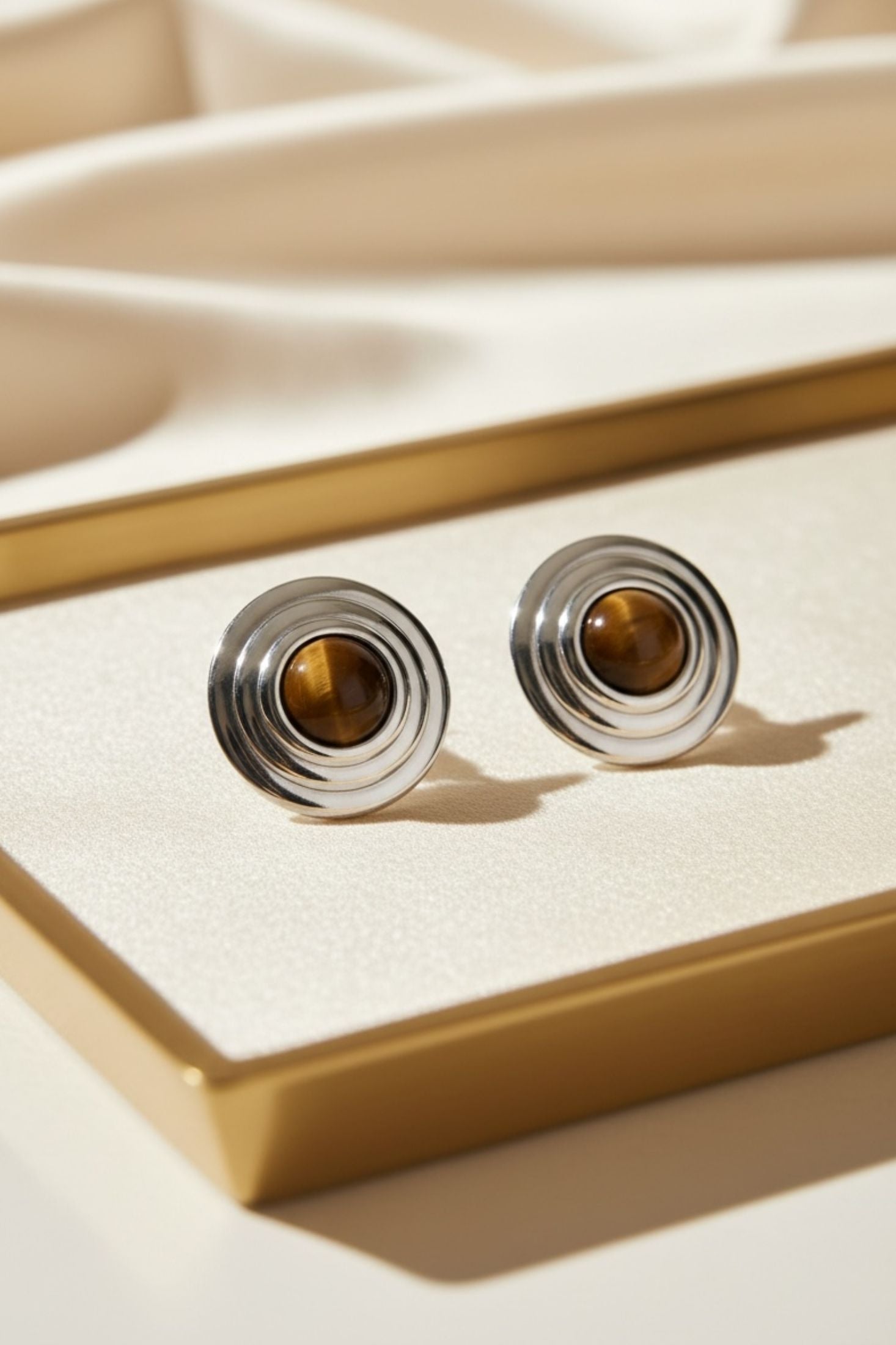 Pair of earrings with brown gemstones on a beige surface