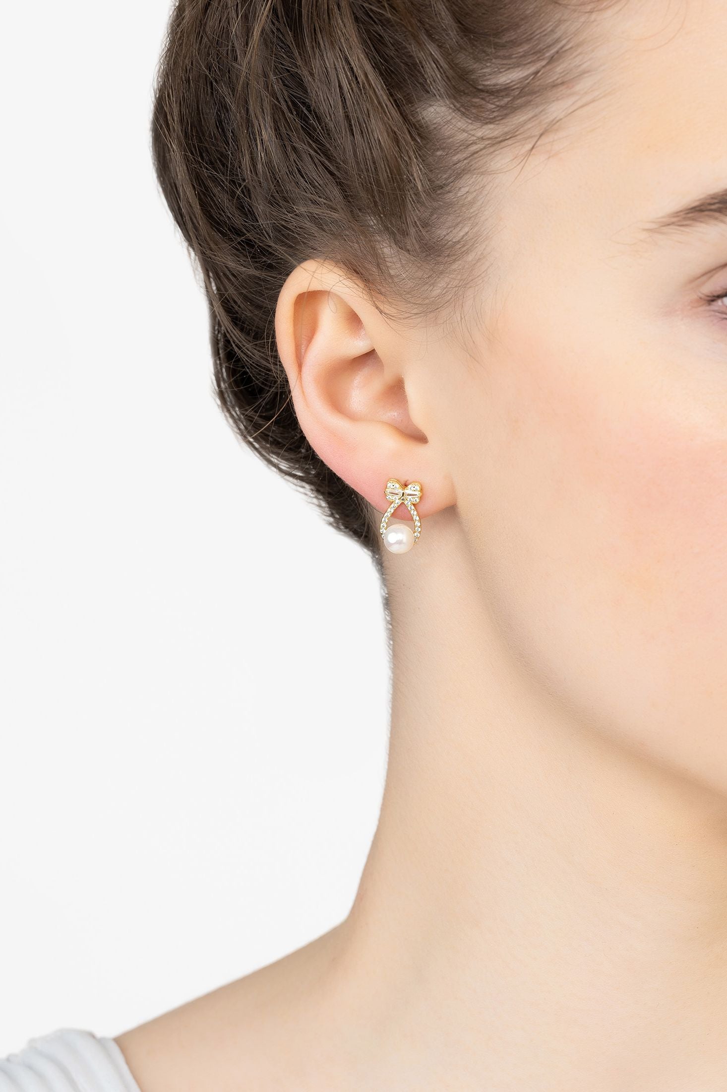 Angled view of Bows And Pearls Earrings Gold, showing bow design, pearl detailing, gold finish and the jewellery profile.