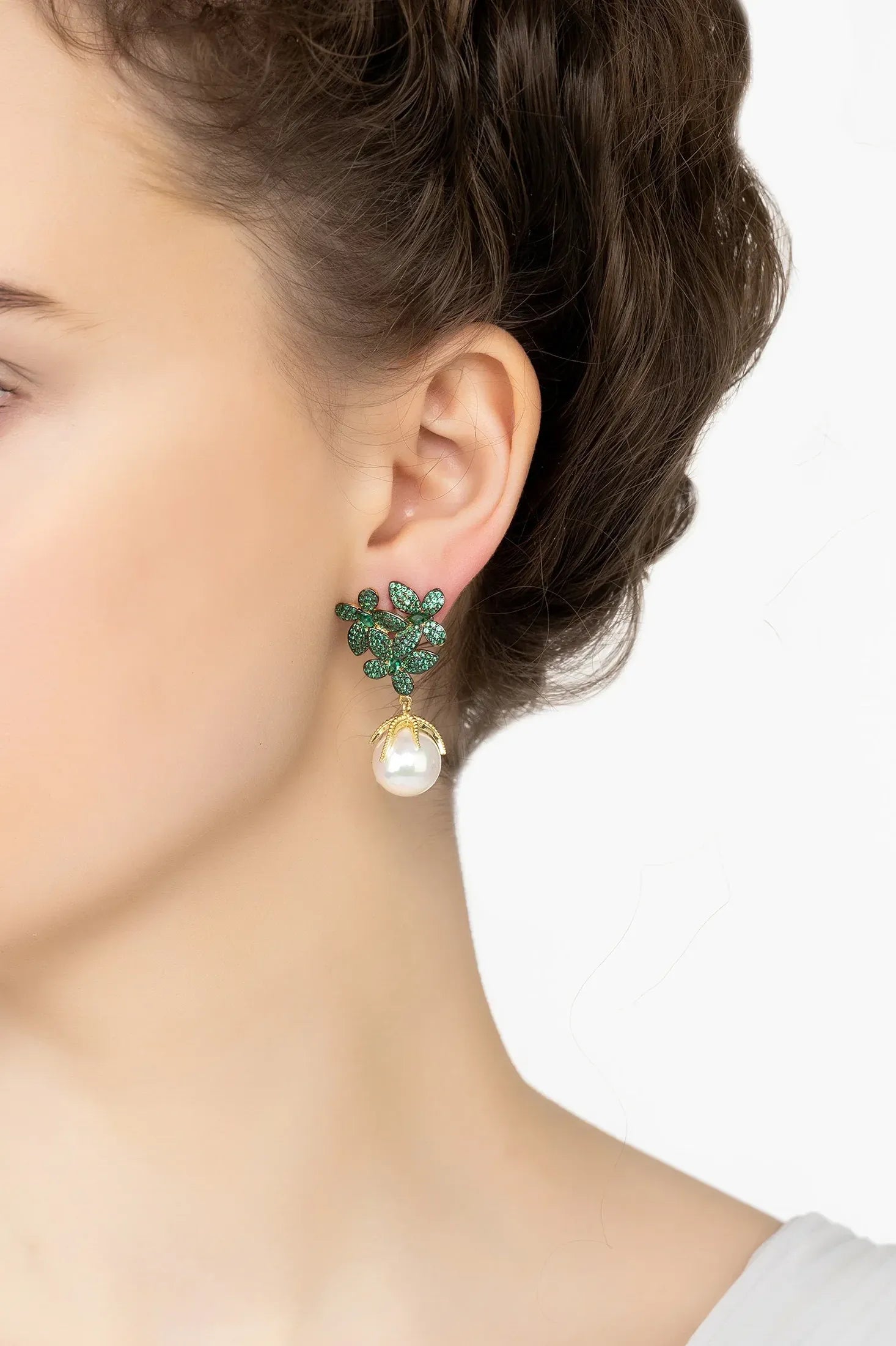 Angled view of Flowers Pearl Earrings Emerald Green Gold, showing flower design, pearl and emerald detailing, gold finish and the jewellery profile.
