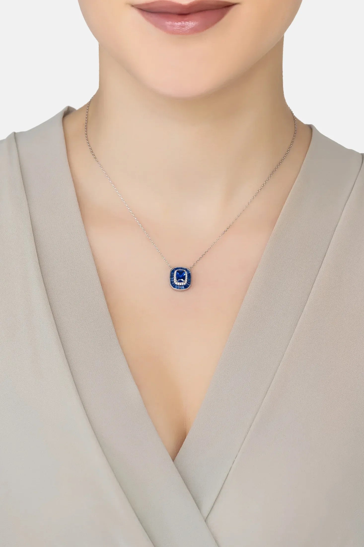 Necklace with a blue pendant worn by a person in a neutral setting