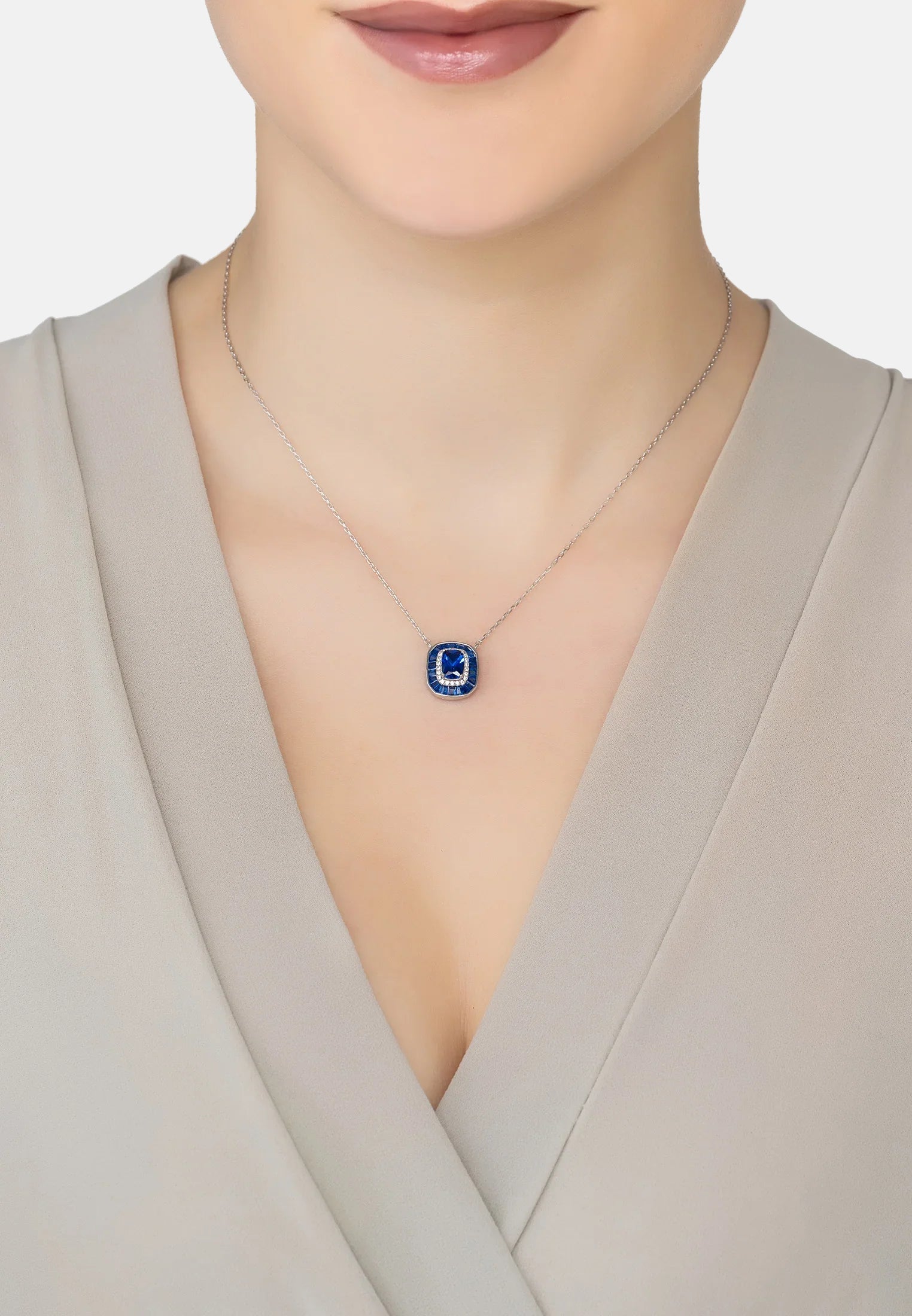 Necklace with a blue pendant worn by a person in a neutral setting