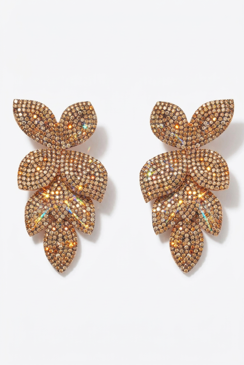 A pair of gold-toned leaf-shaped stud earrings covered in small iridescent rhinestones, displayed on a clean white background.