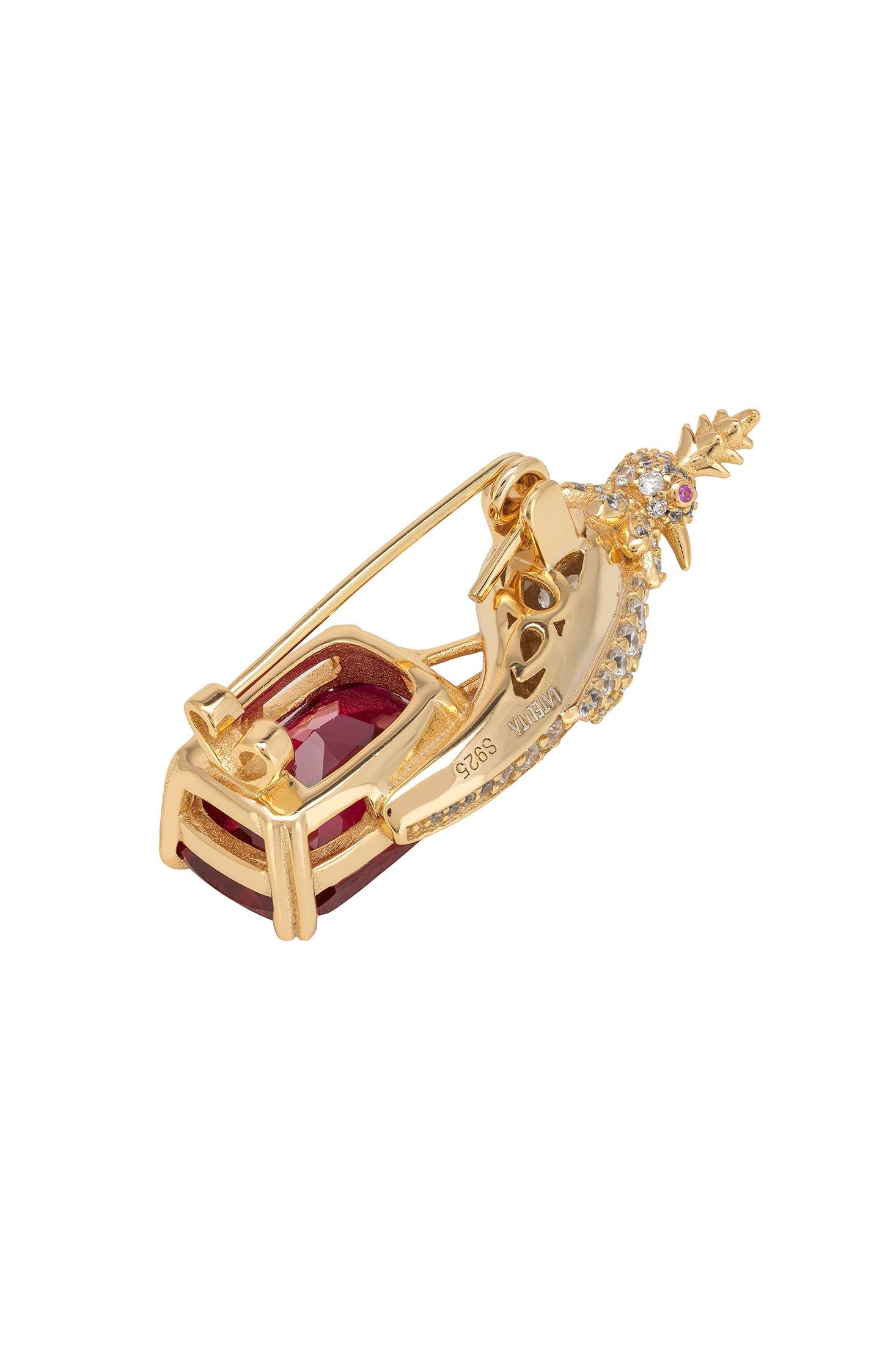 Gold bird inspired brooch with a red gemstone on a white background