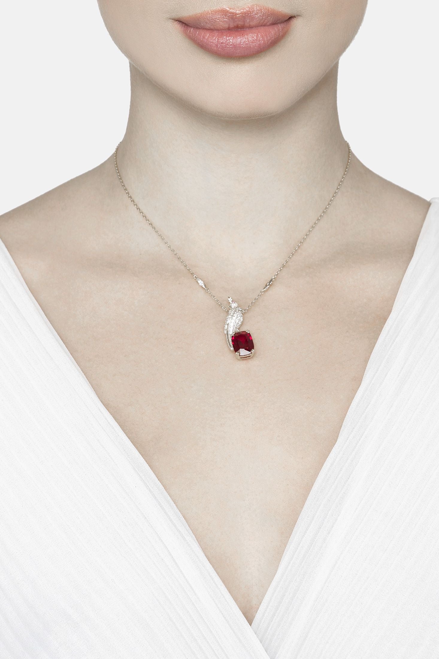 Angled view of Crested Love Bird Pendant Necklace Ruby Silver, showing bird design, ruby detailing, silver finish and the jewellery profile.