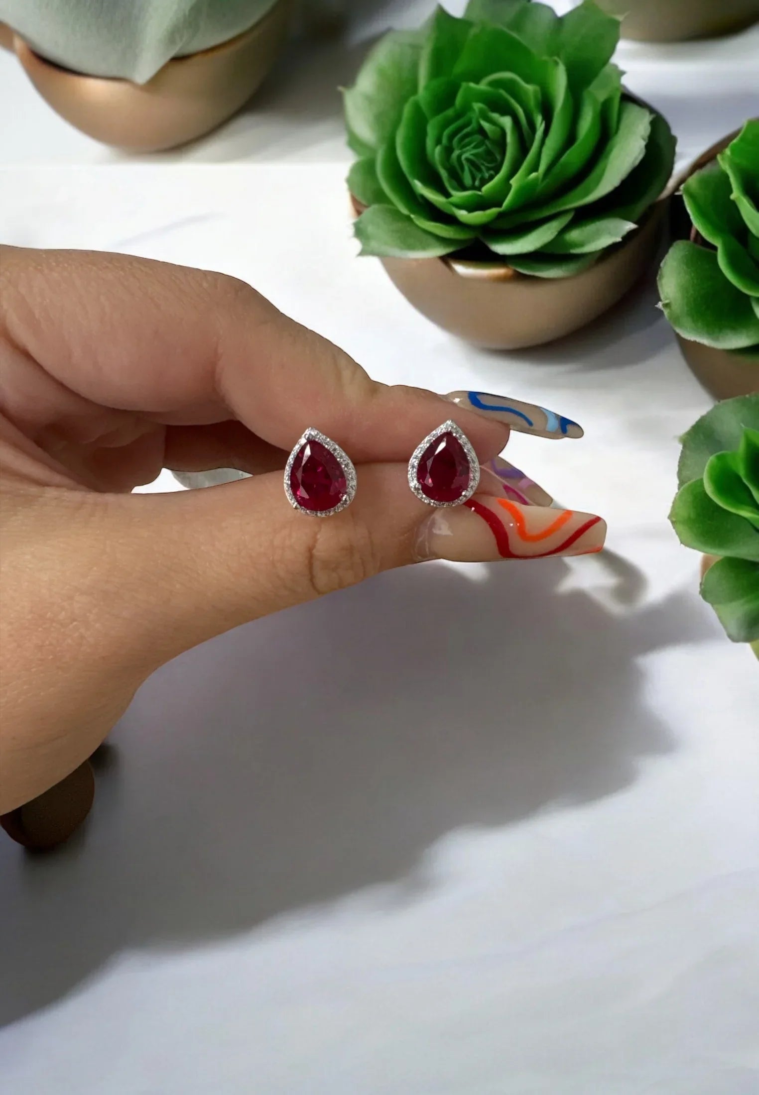 The earrings held up by a hand model.