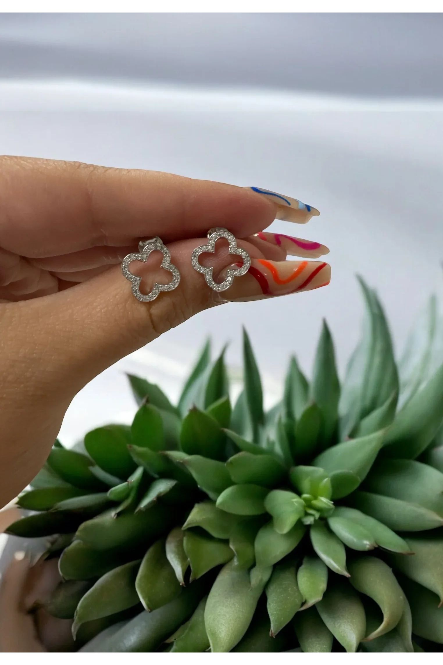 The earrings held up by a hand model.