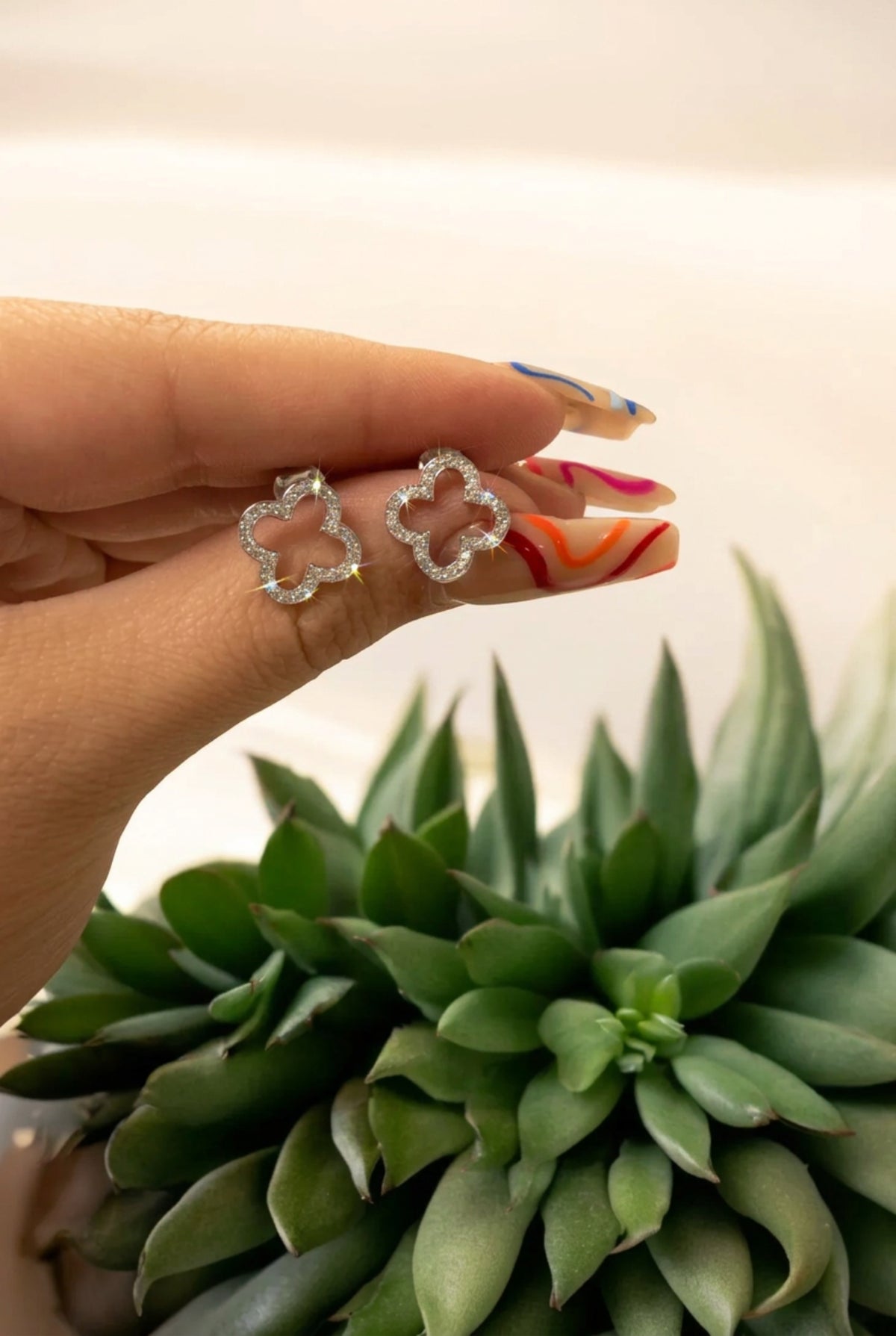 The earrings held up by a hand model.