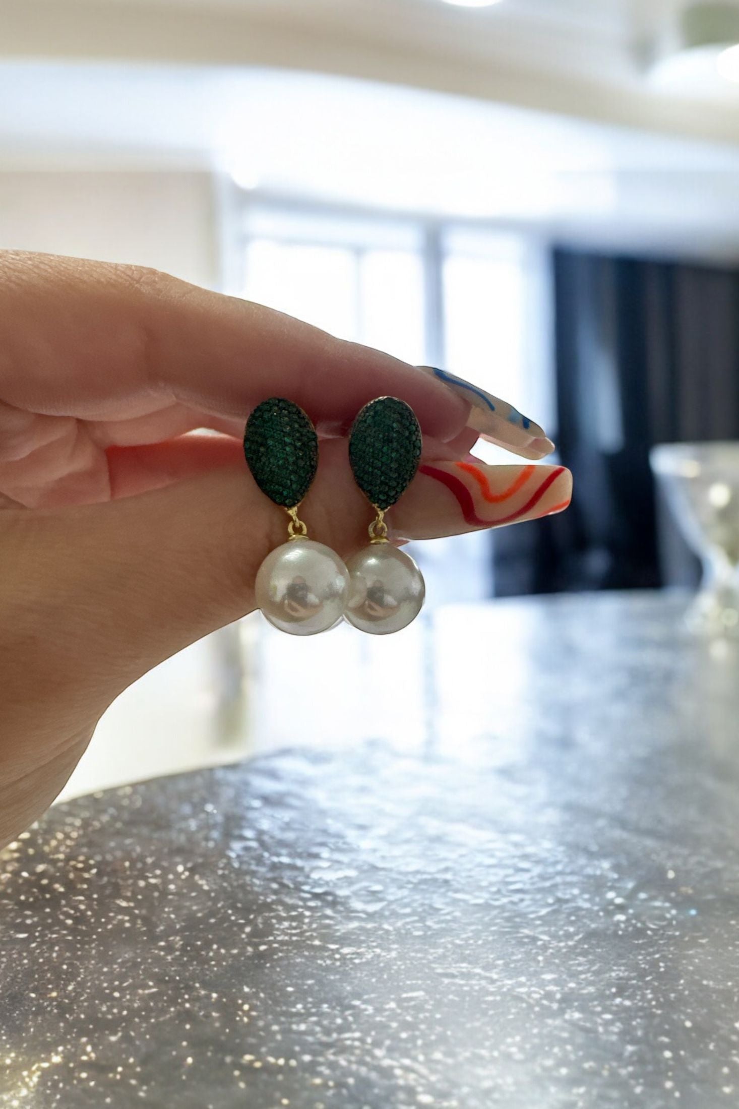 The earrings held up by a hand model.