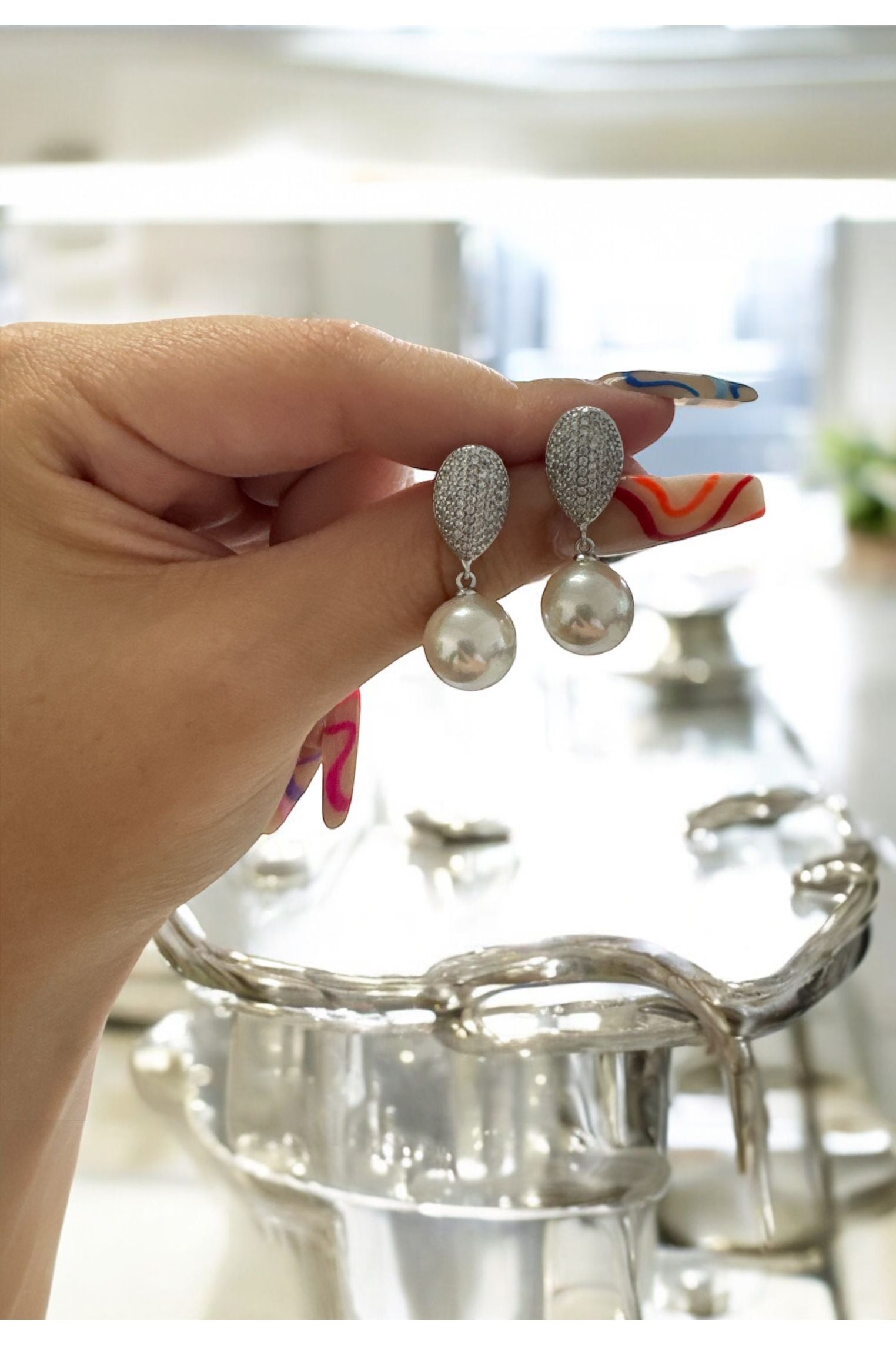 The earrings held up by a hand model.