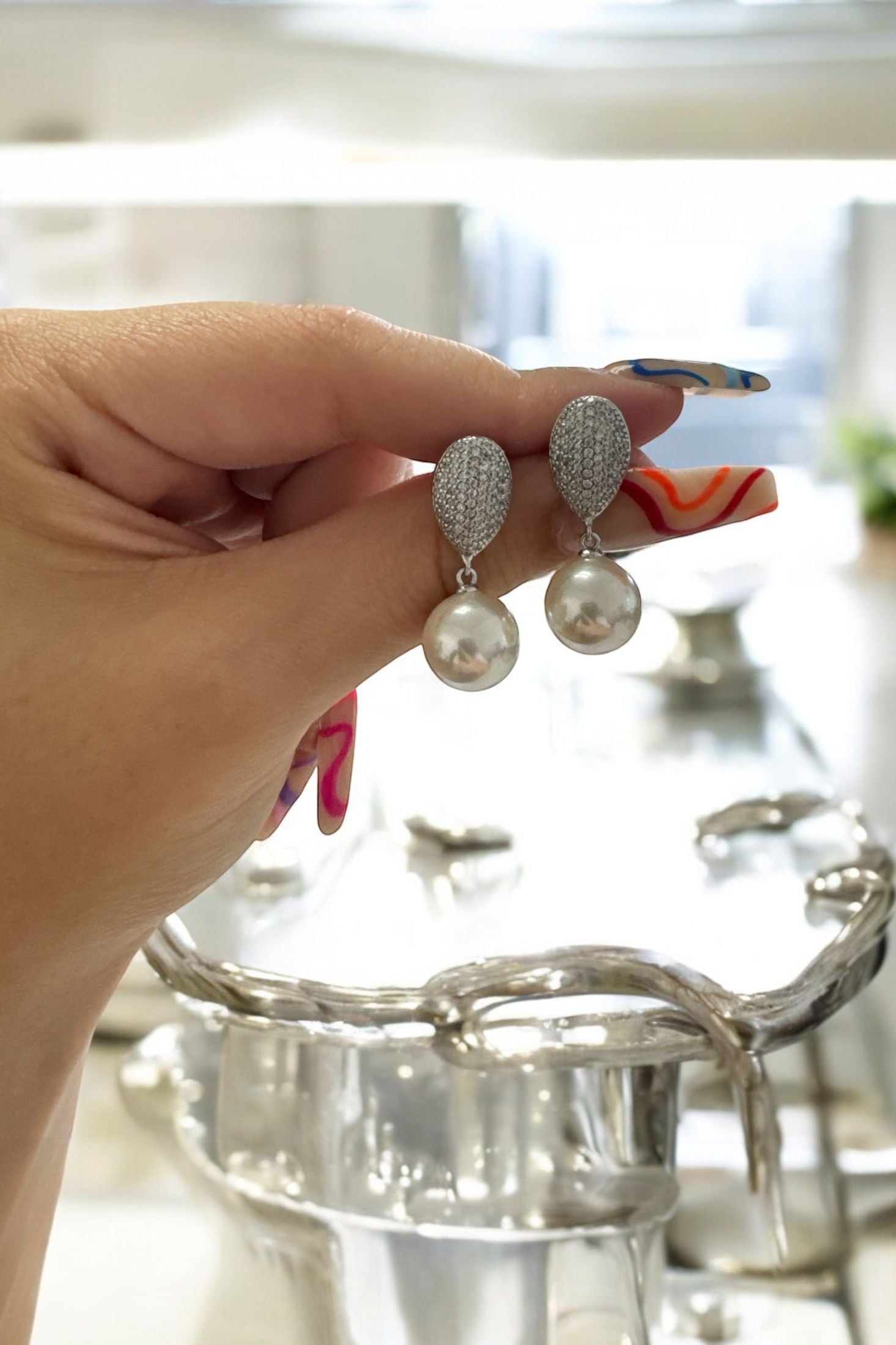 The earrings held up by a hand model.