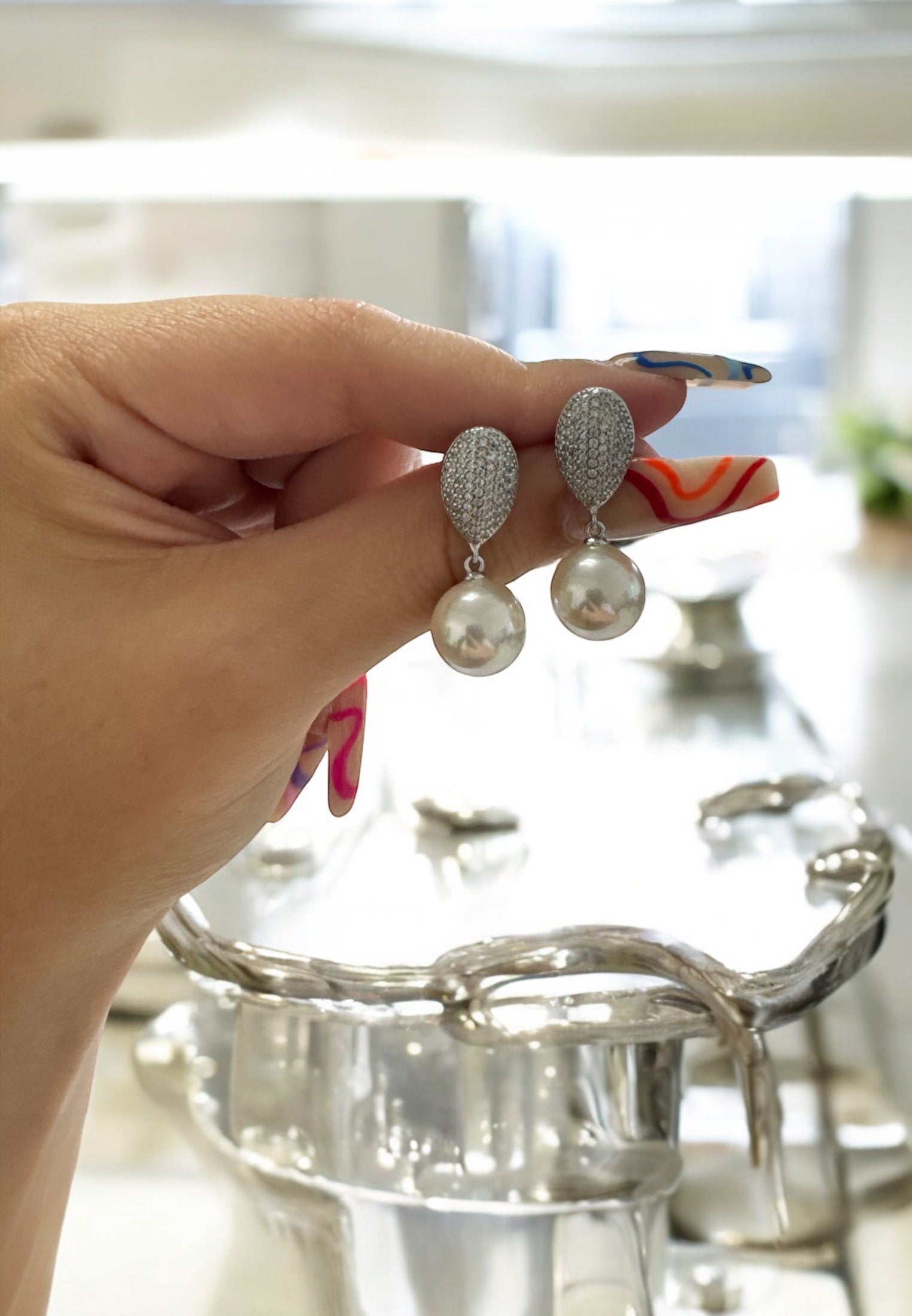 The earrings held up by a hand model.