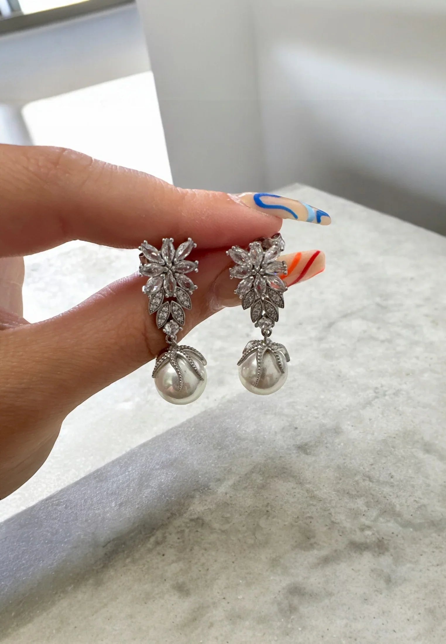 The earrings held up by a hand model.
