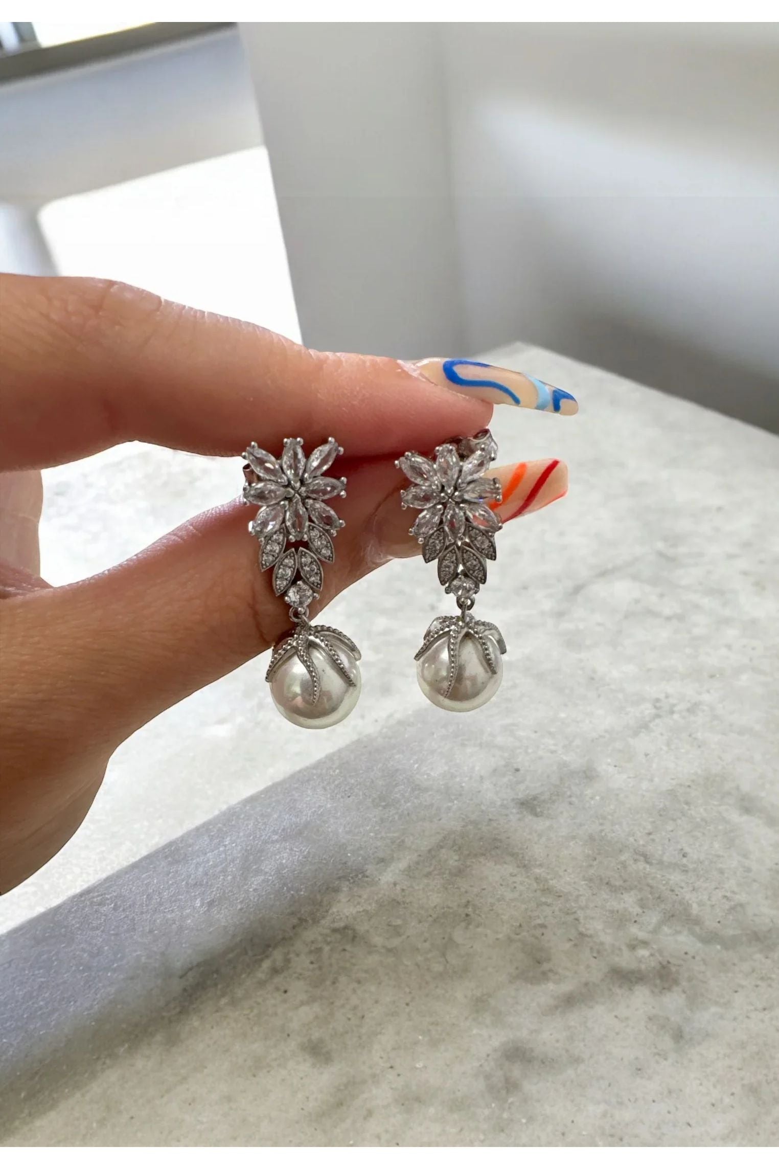 The earrings held up by a hand model.