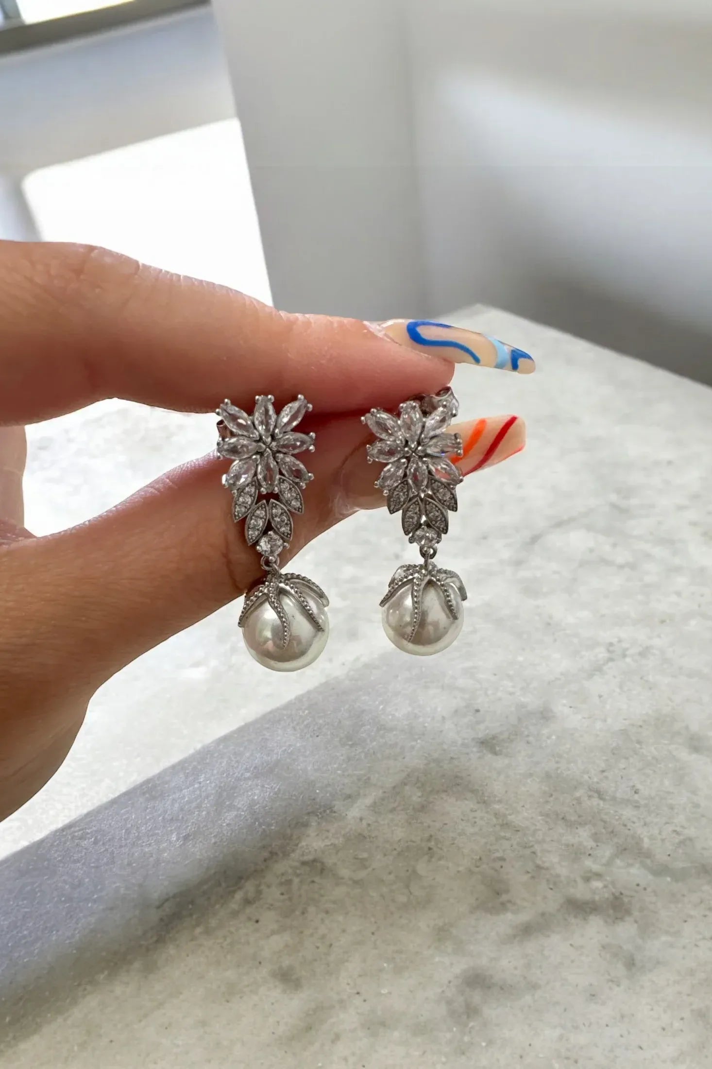 The earrings held up by a hand model.