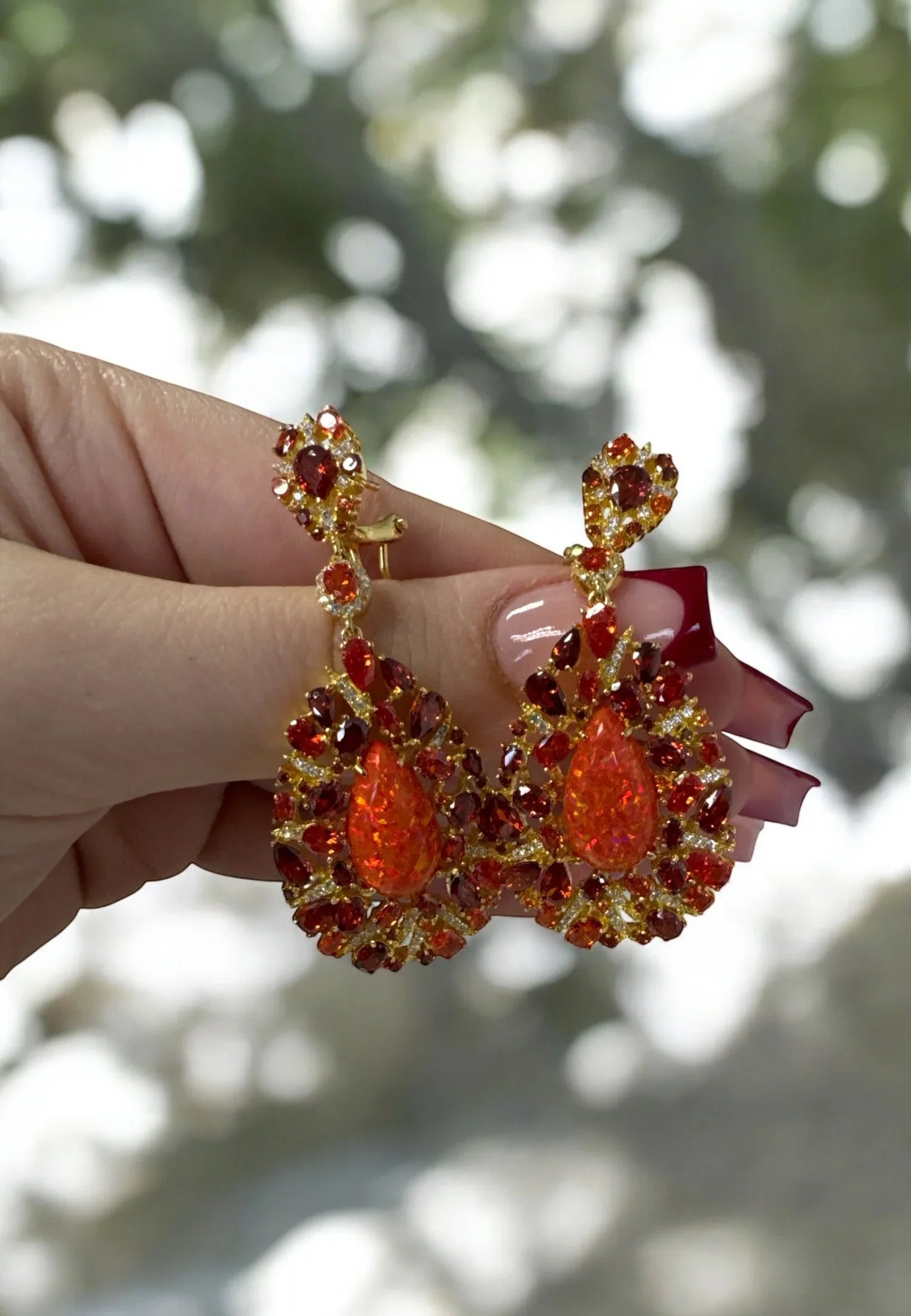 The earrings held up by a hand model.