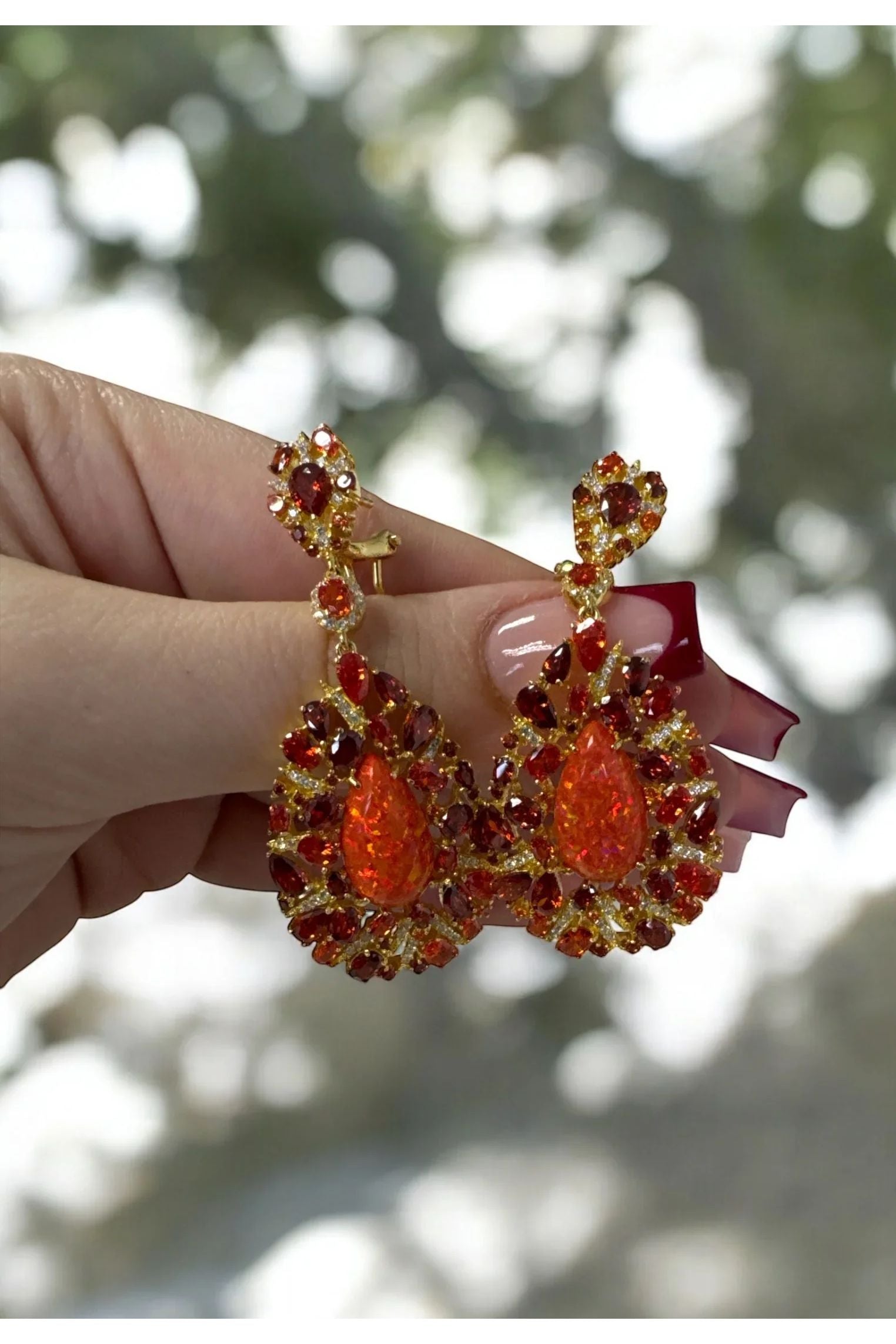 The earrings held up by a hand model.