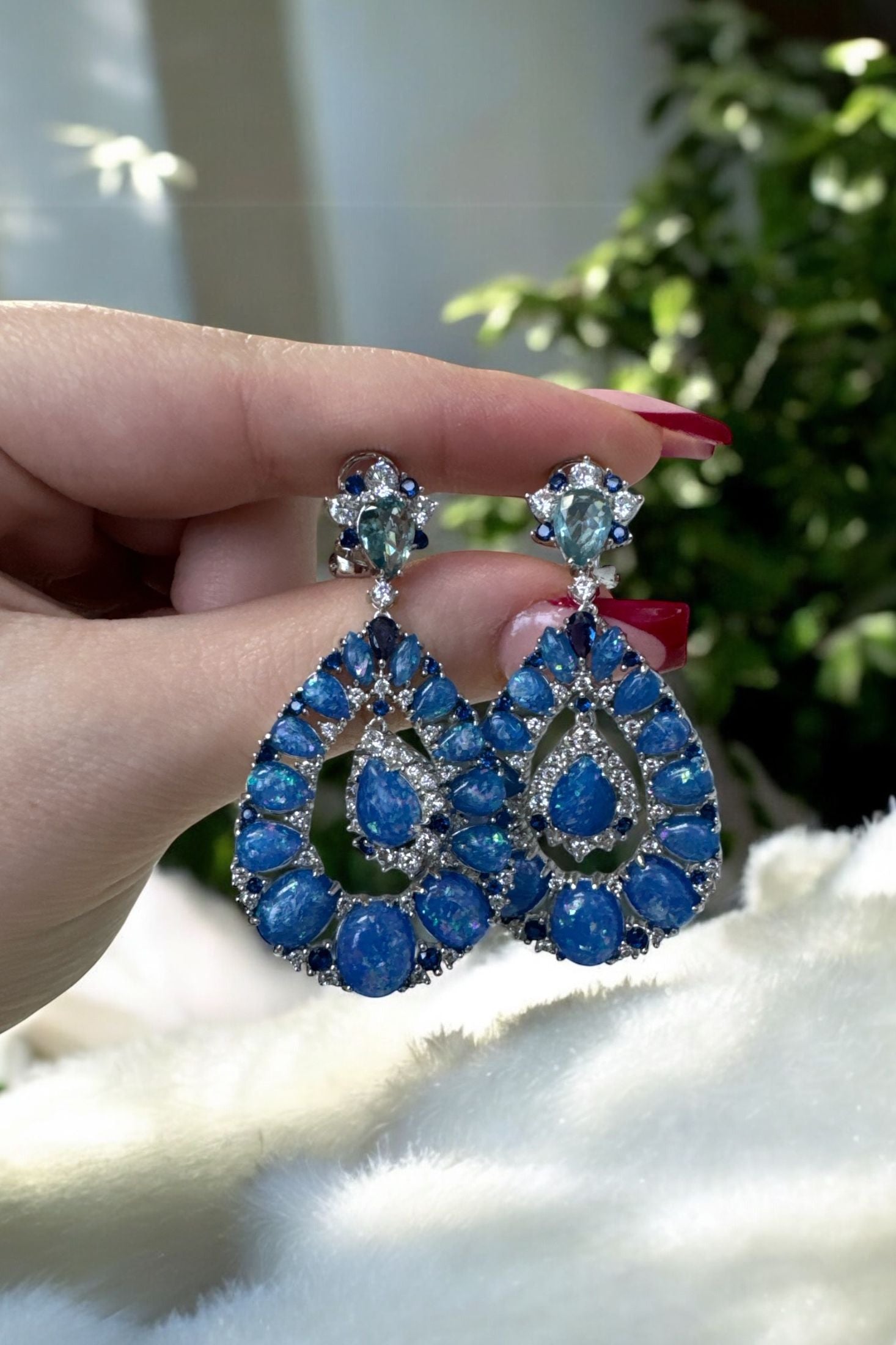 The earrings held up by a hand model.