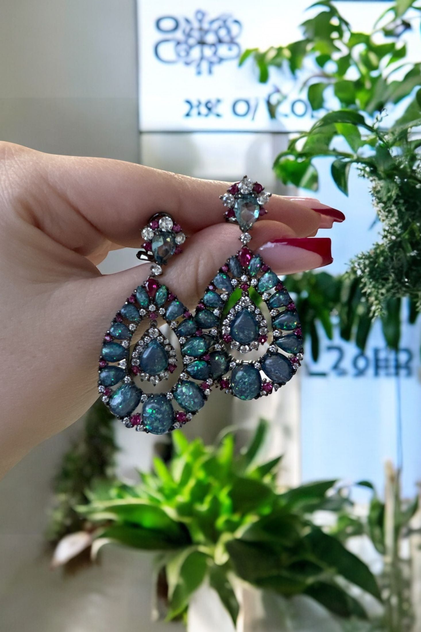 The earrings held up by a hand model.