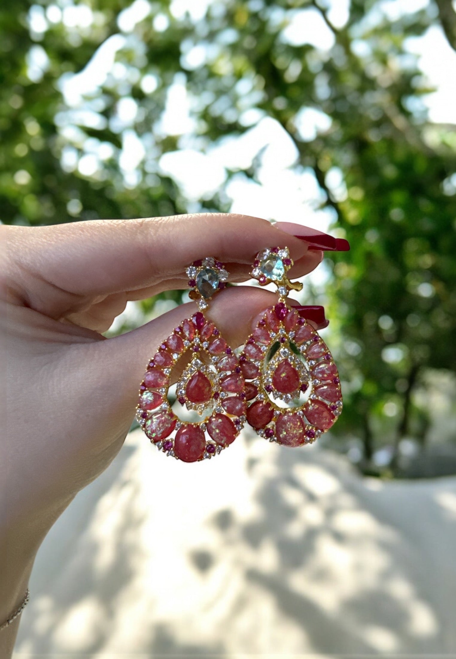 The earrings held up by a hand model.