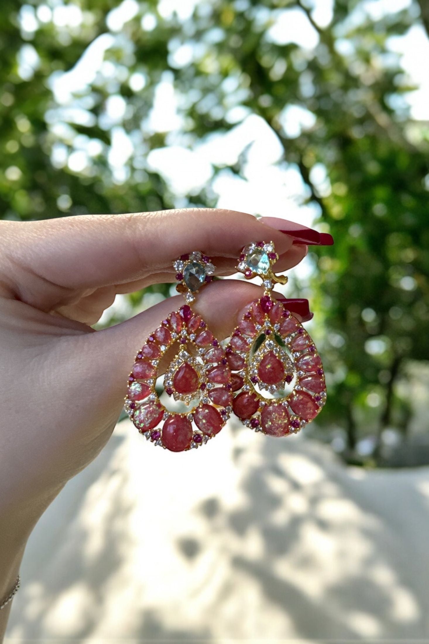 The earrings held up by a hand model.