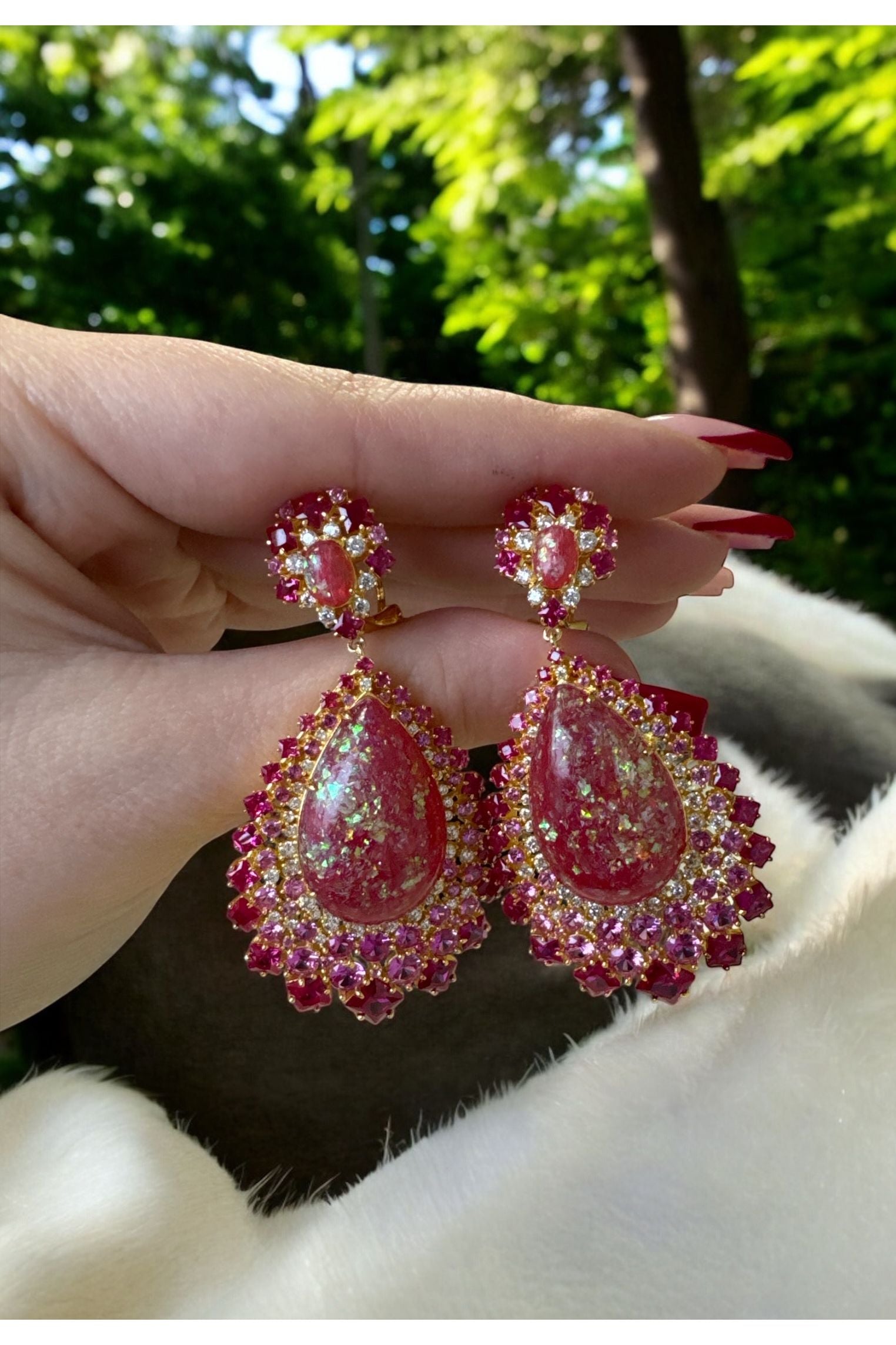 The earrings held up by a hand model.