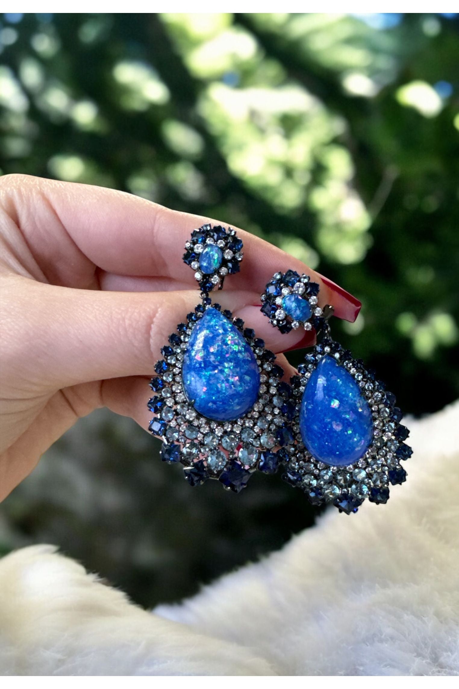 The earrings held up by a hand model.