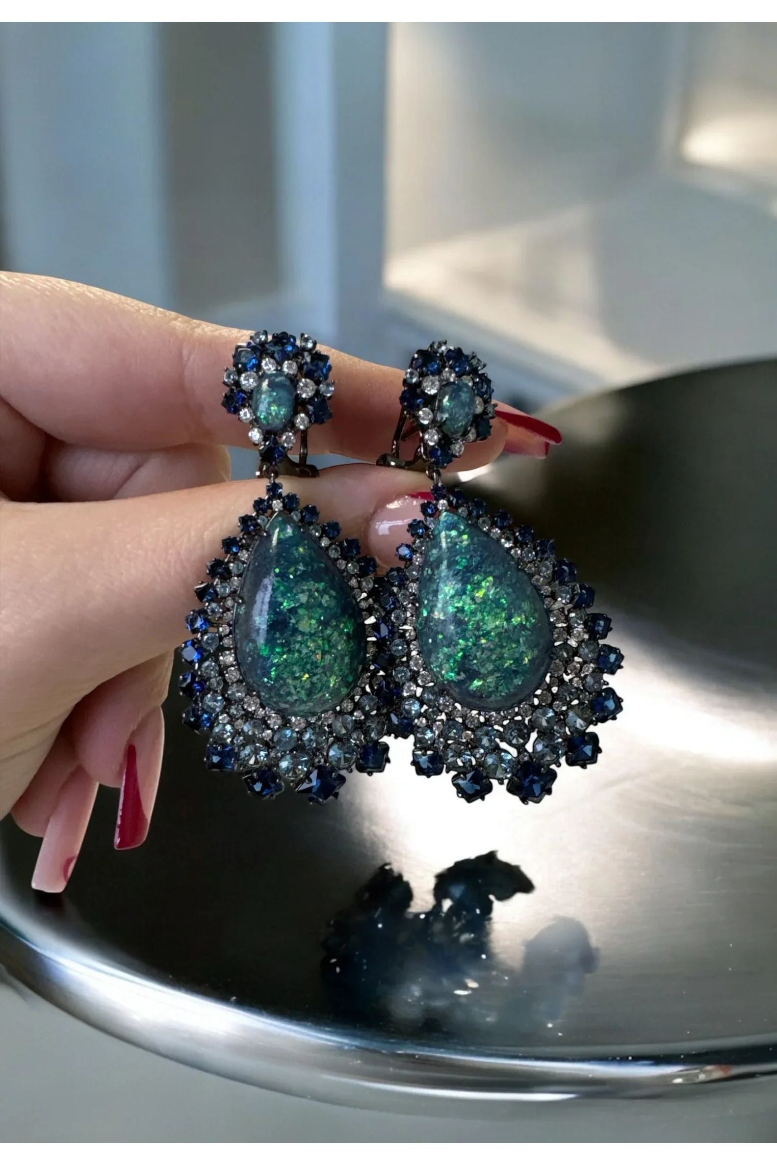 The earrings held up by a hand model.