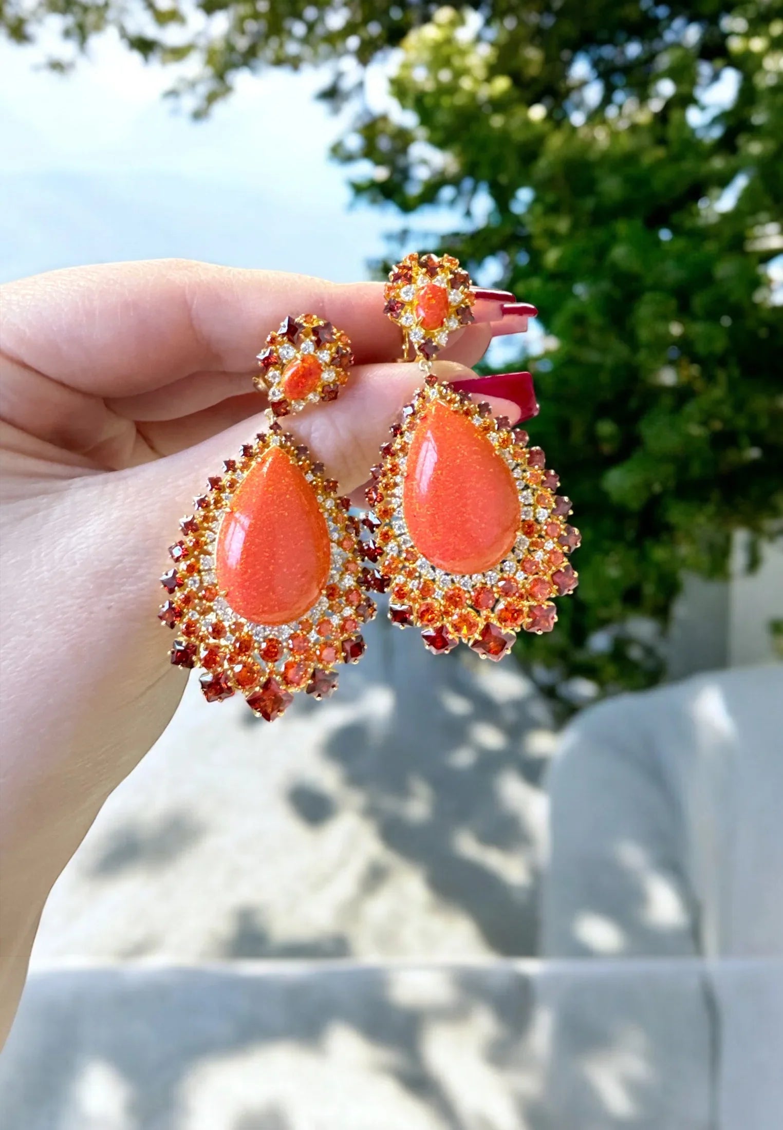 The earrings held up by a hand model.