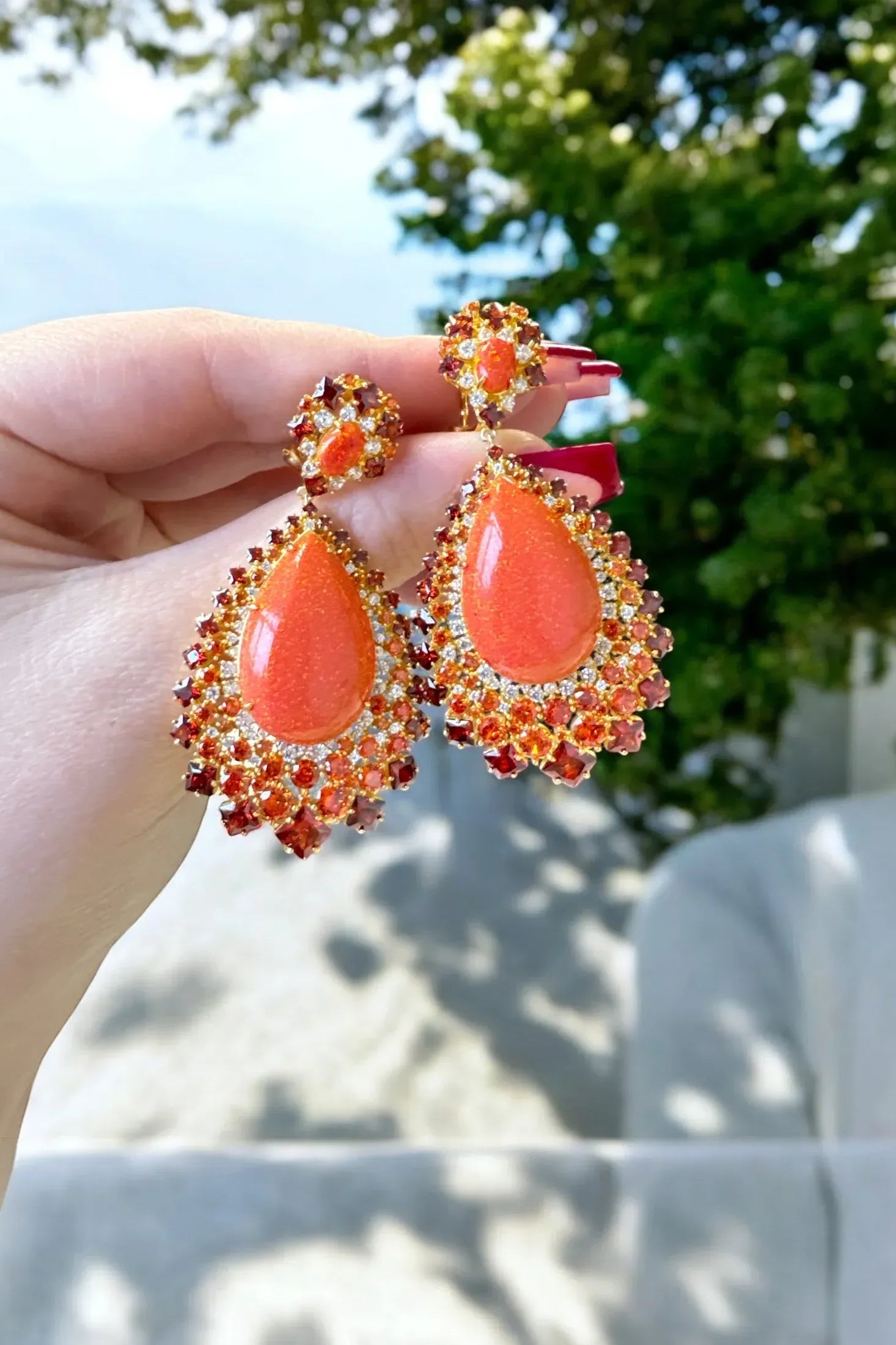 The earrings held up by a hand model.