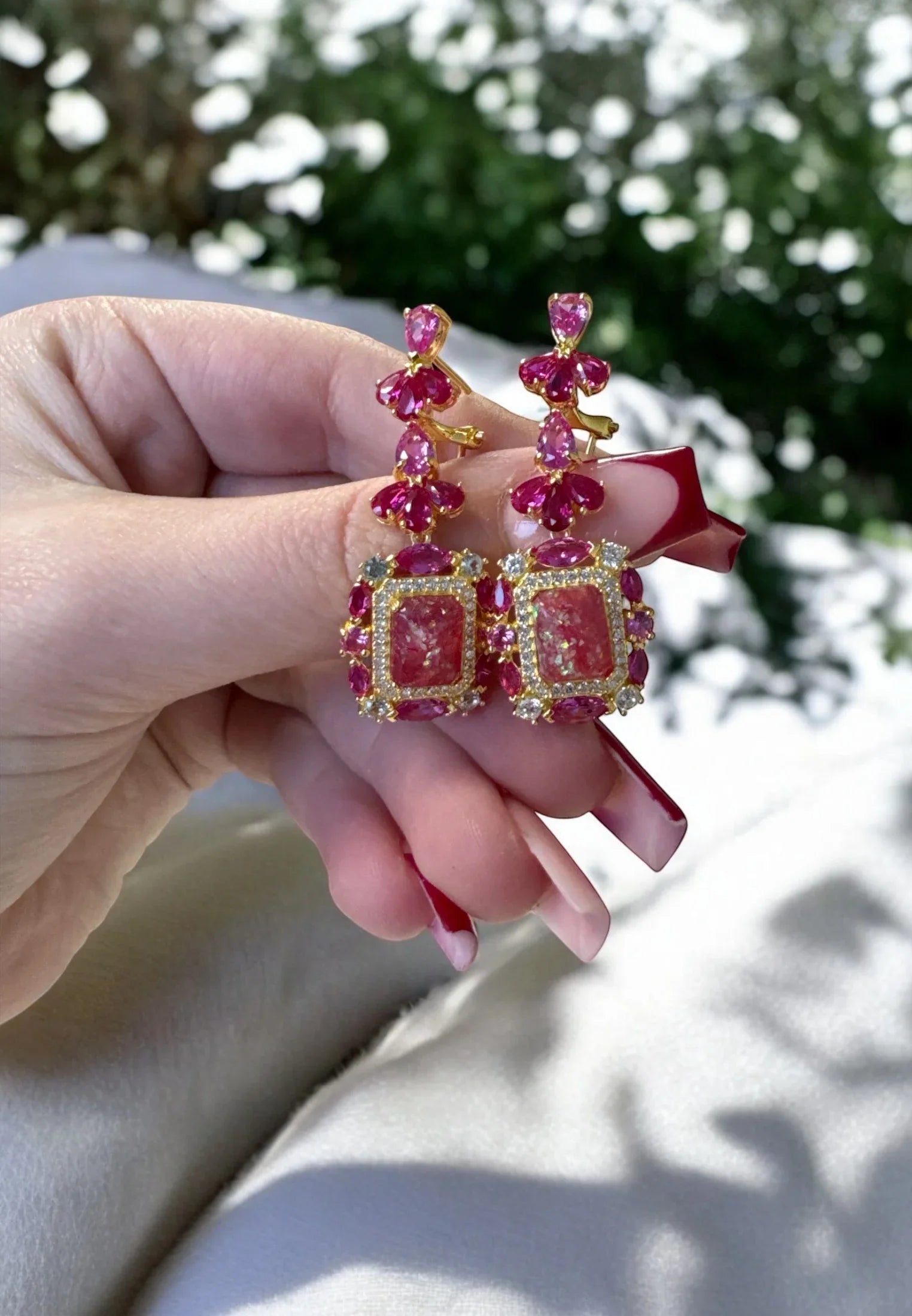The earrings held up by a hand model.