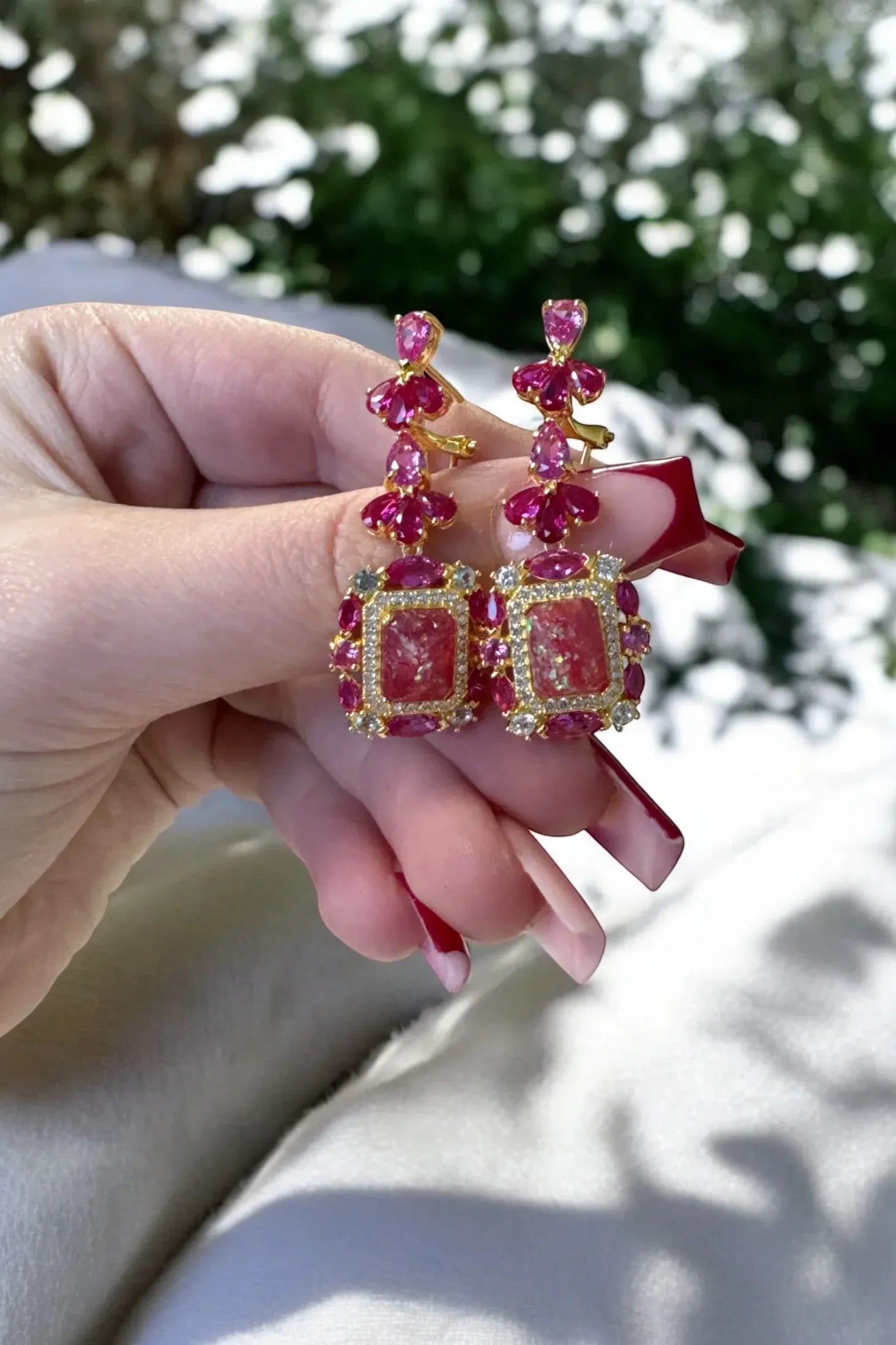 The earrings held up by a hand model.