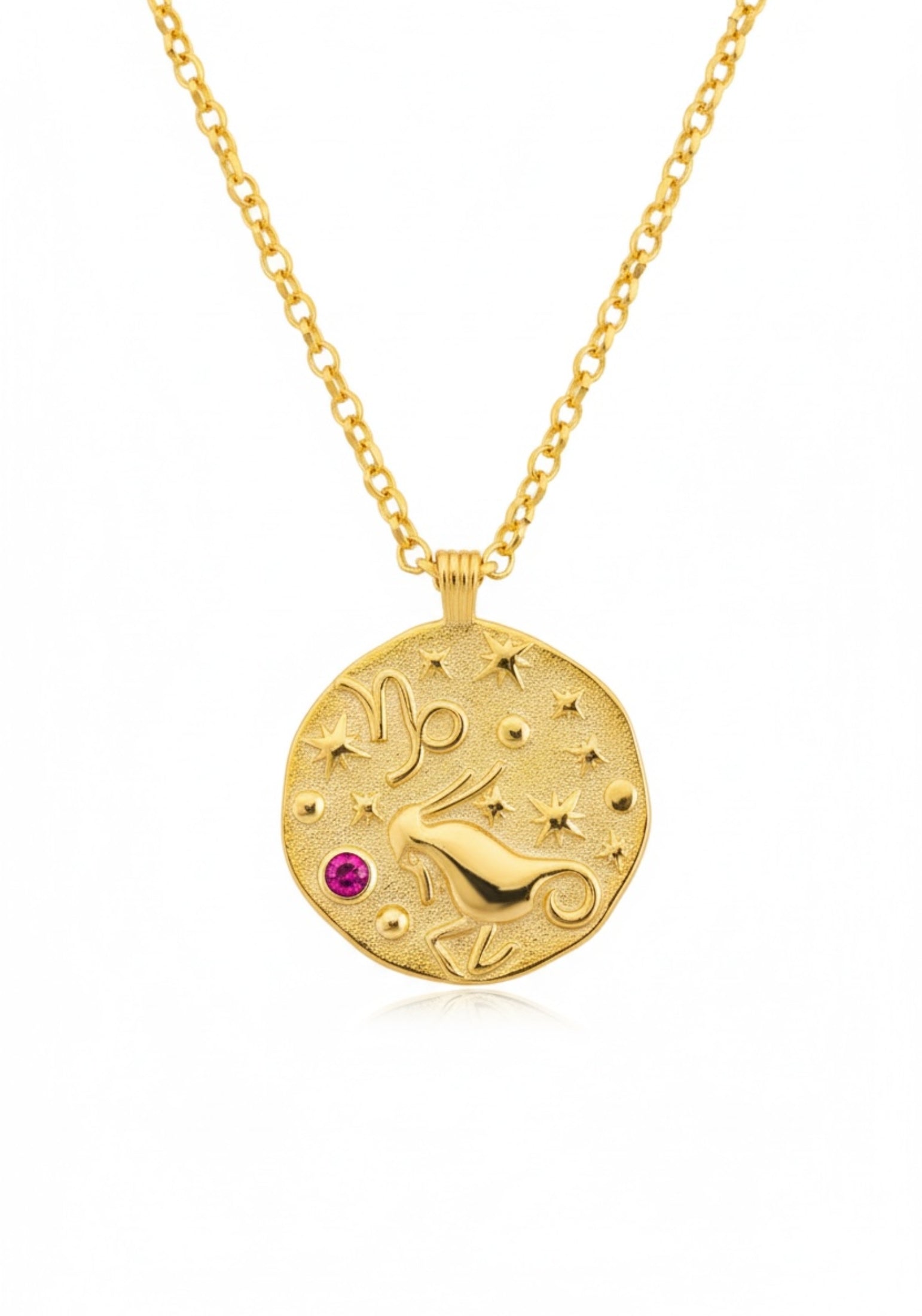 Gold necklace with a circular pendant featuring a design and a red gemstone on a white background