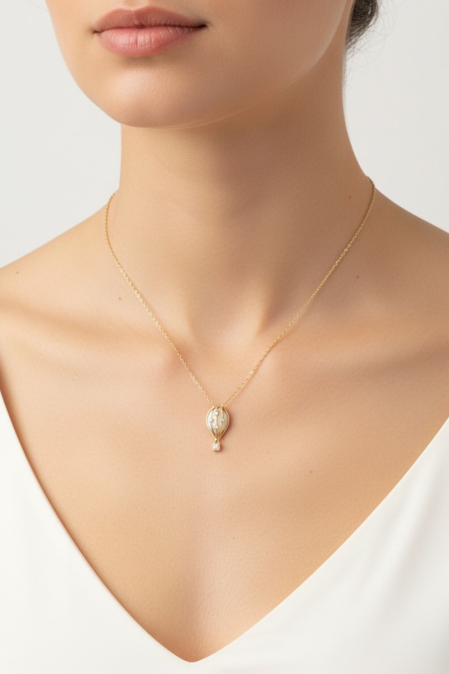 Gold necklace with a hot air balloon pendant on a model against a white background