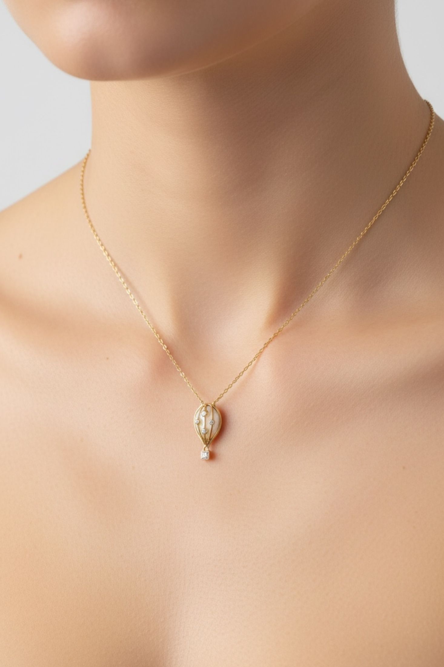 Gold necklace with a hot air balloon pendant on a woman