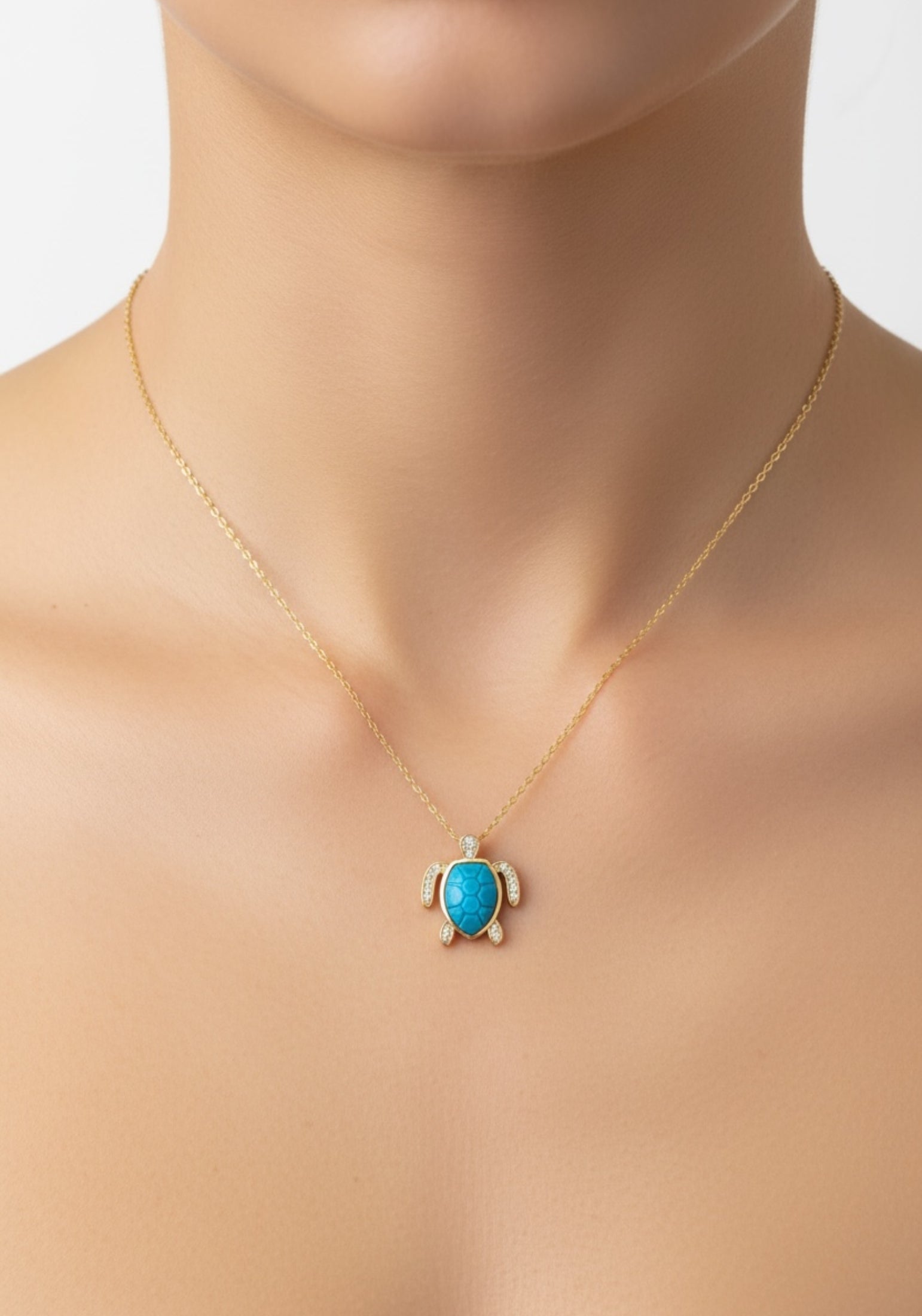 Turquoise turtle pendant necklace on a woman with a plain background