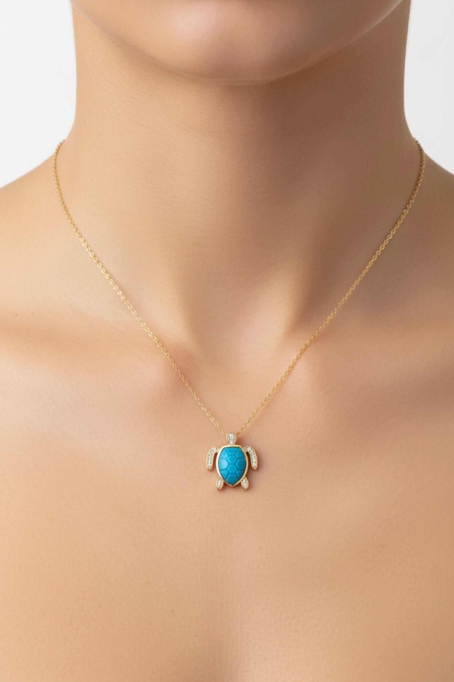 Turquoise turtle pendant necklace on a woman with a plain background