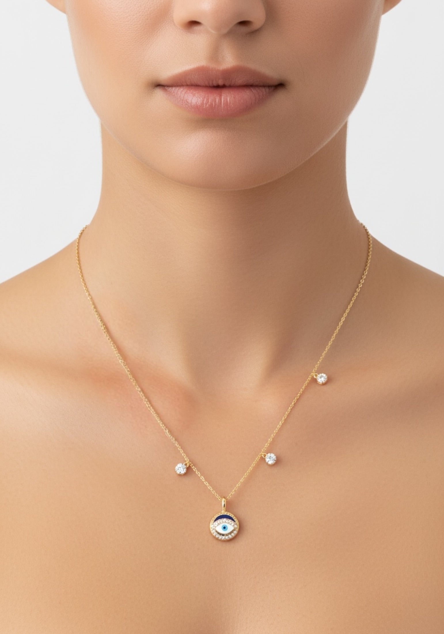 Gold necklace with an evil eye pendant worn by a model on a neutral background