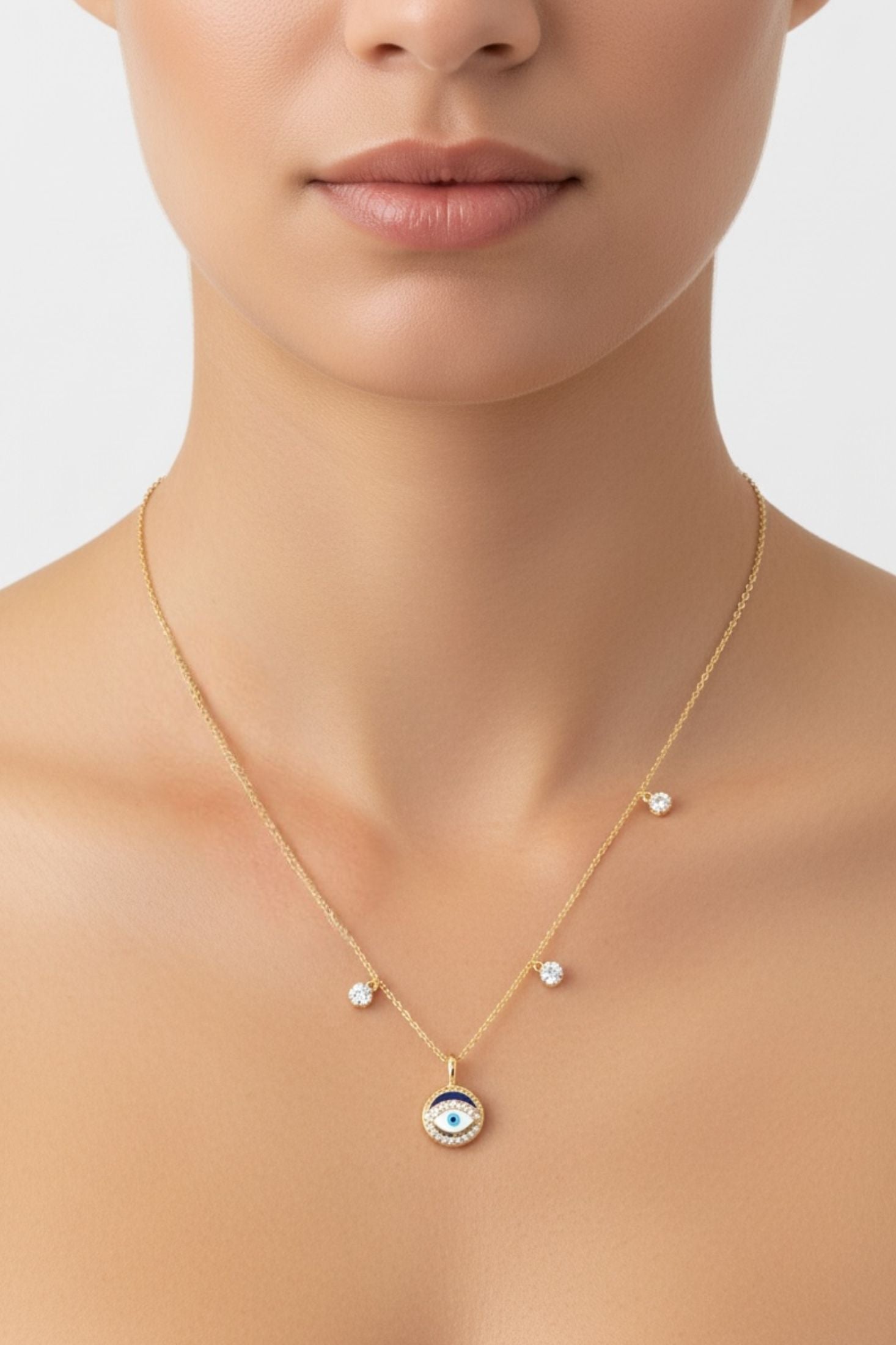 Gold necklace with an evil eye pendant worn by a model on a neutral background