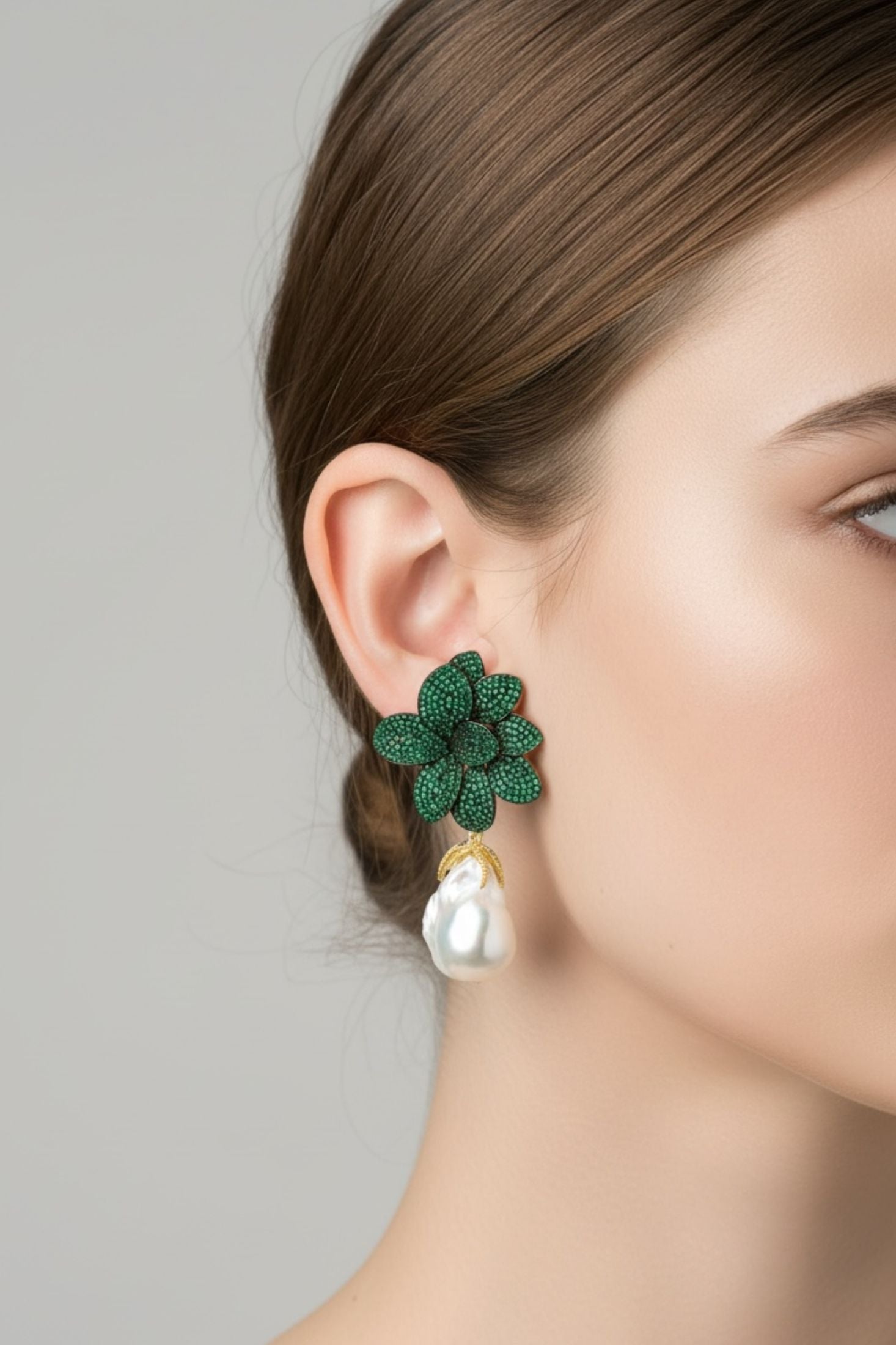 Green floral earring with pearl detail worn by a model on a plain background
