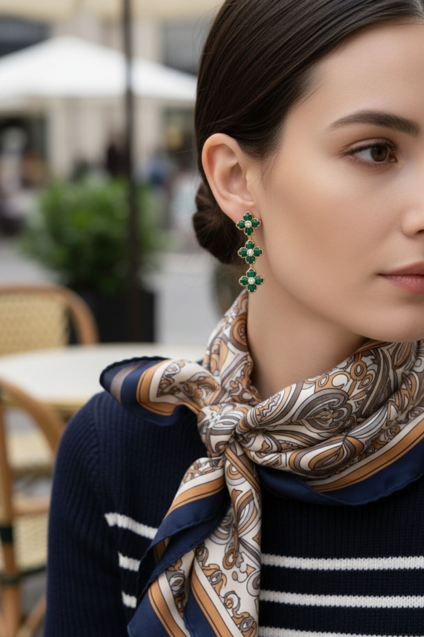 Woman wearing a patterned scarf and green clover earrings in an outdoor setting