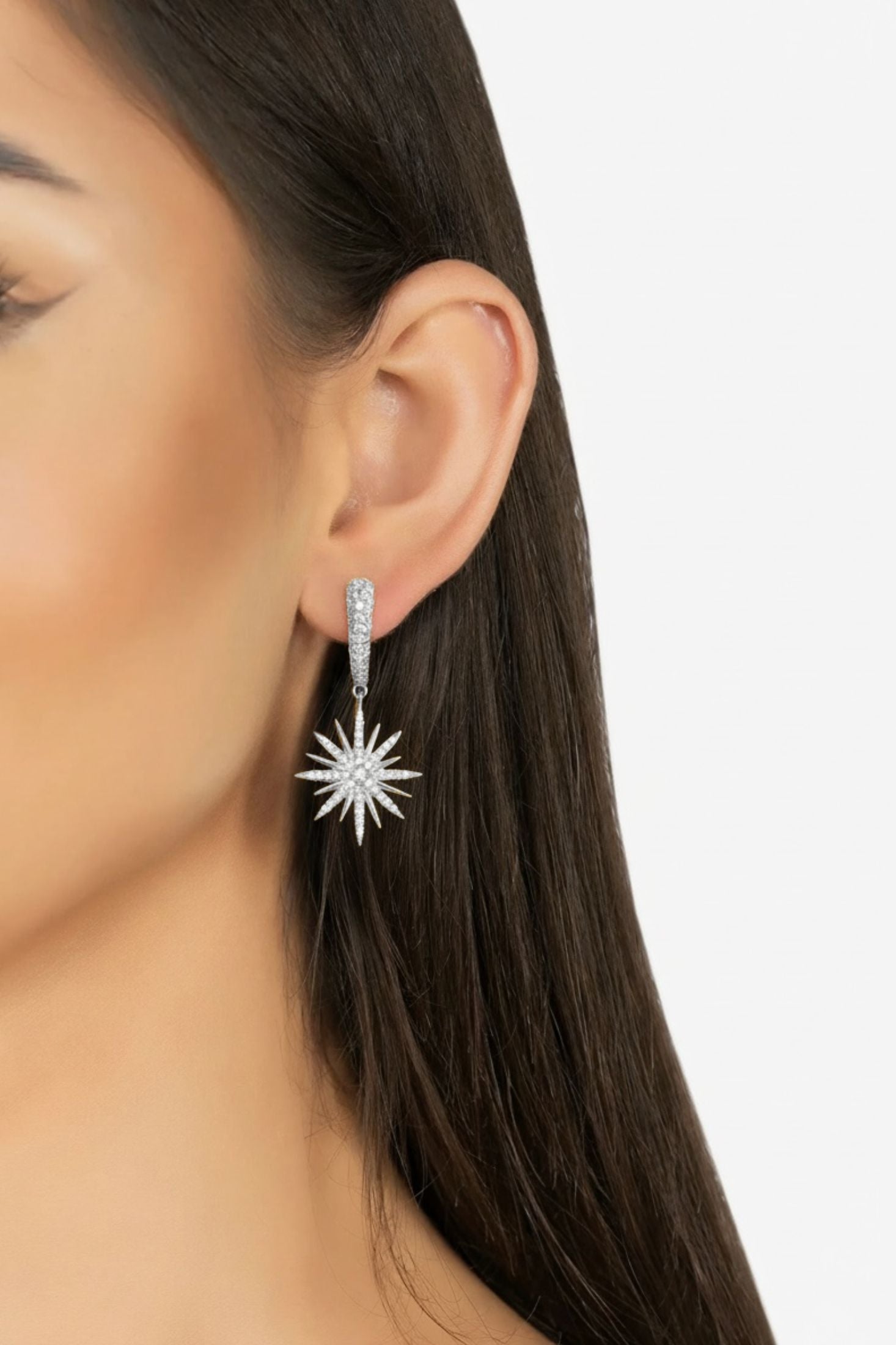 Close-up of a person wearing a star-shaped earring on a plain background