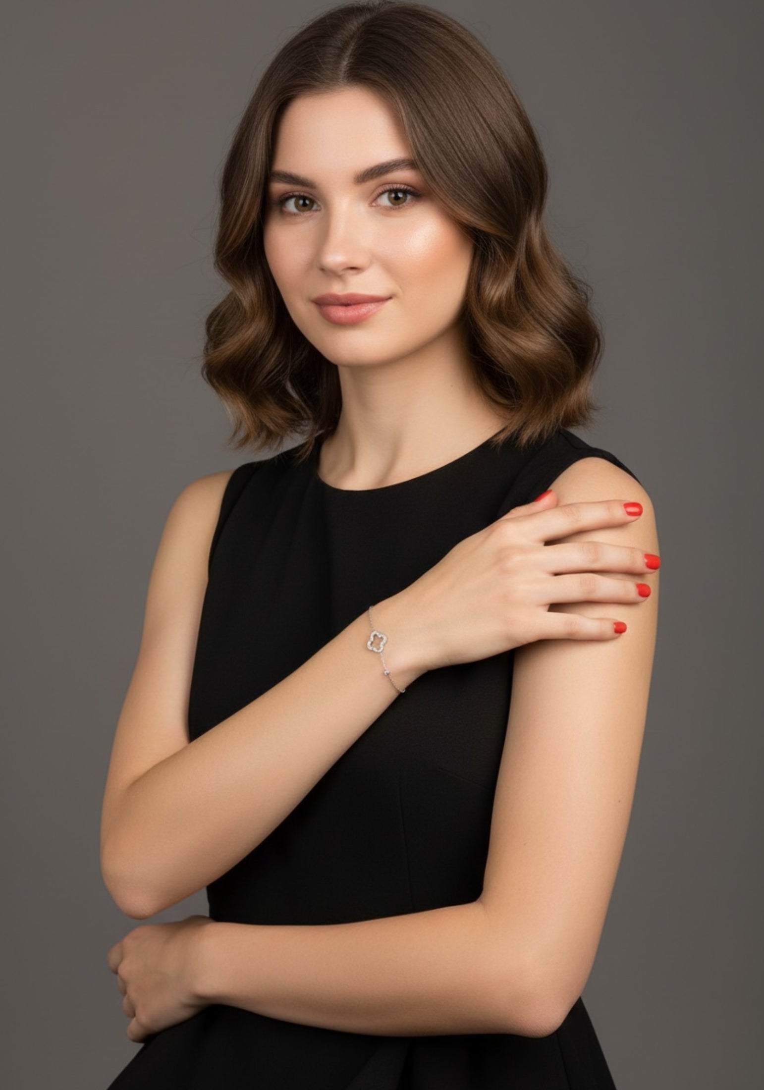 Woman in a black dress against a gray background wearing a silver clover bracelet