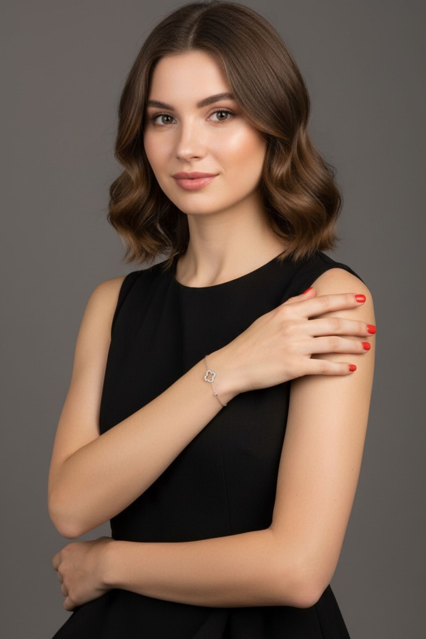 Woman in a black dress against a gray background wearing a silver clover bracelet